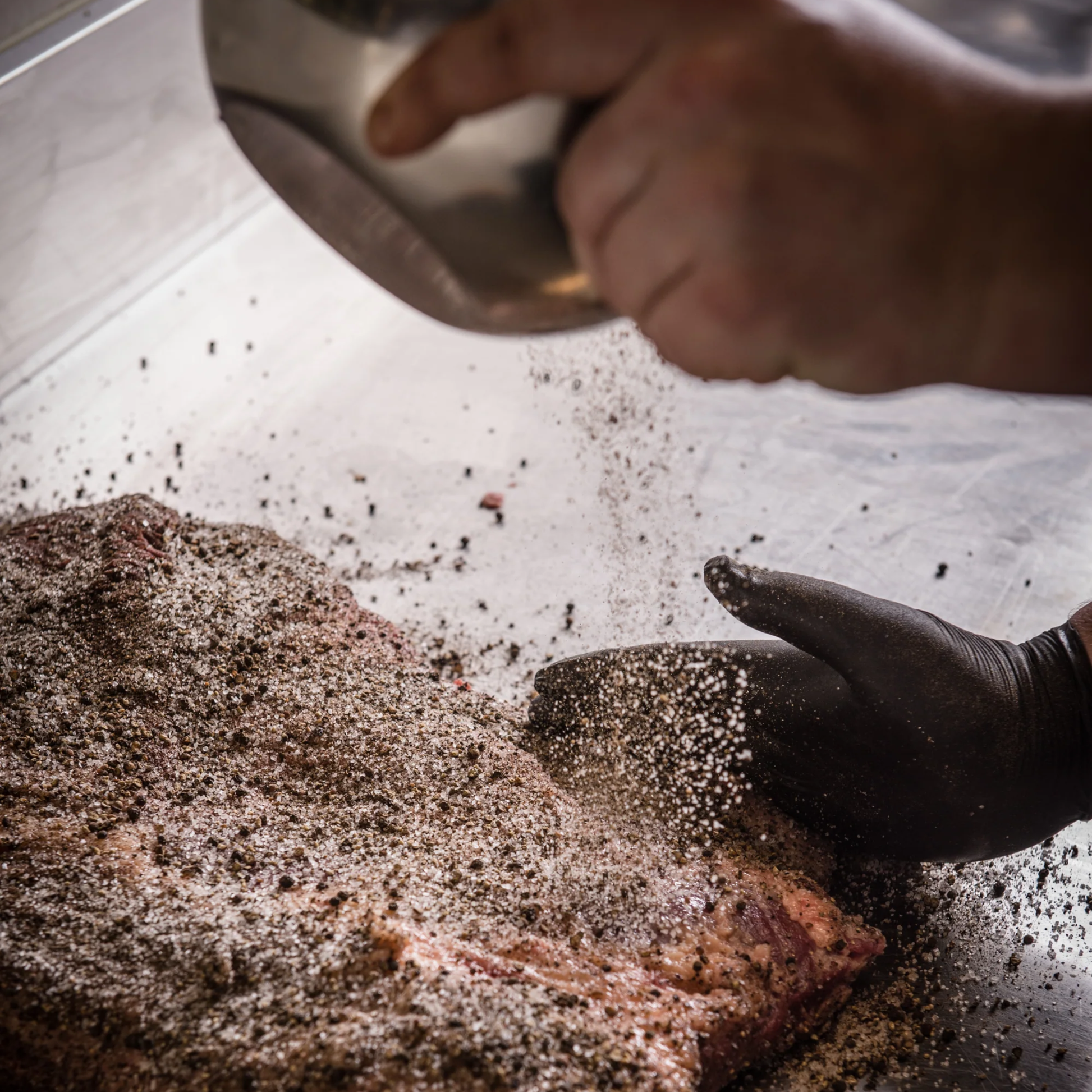 Seasoning the meat before grilling with the Fancy Hanks BBQ Pepper 90g, a bold pepper-forward seasoning rub designed for meat.