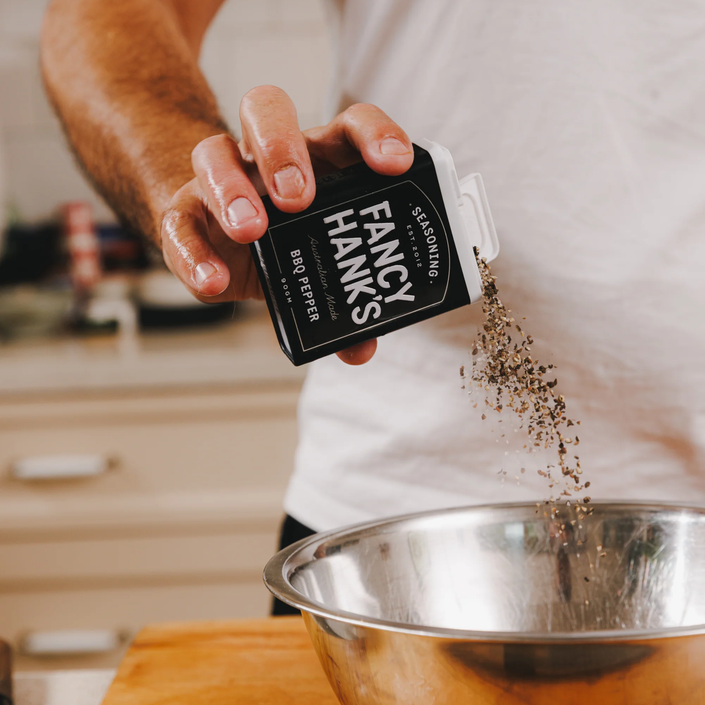 A person adding the Fancy Hanks BBQ Pepper 90g into a bowl, a bold pepper-forward seasoning rub designed for meat.