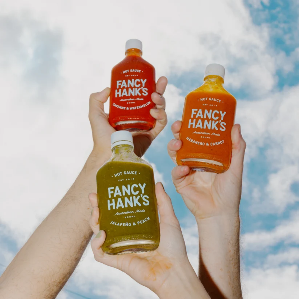 Raising Fancy Hanks Cayenne & Watermelon Hot Sauce 200ml bottle. Vibrant red sauce in a clear glass container with a white lid.