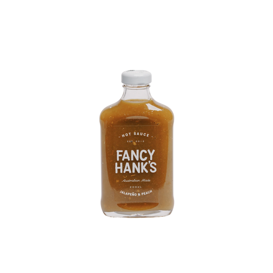 Front view of the Fancy Hanks Jalapeno & Peach Hot Sauce 200ml bottle, orange-yellow sauce in clear glass with white cap; sweet, tangy, medium heat, fruit-forward flavor.