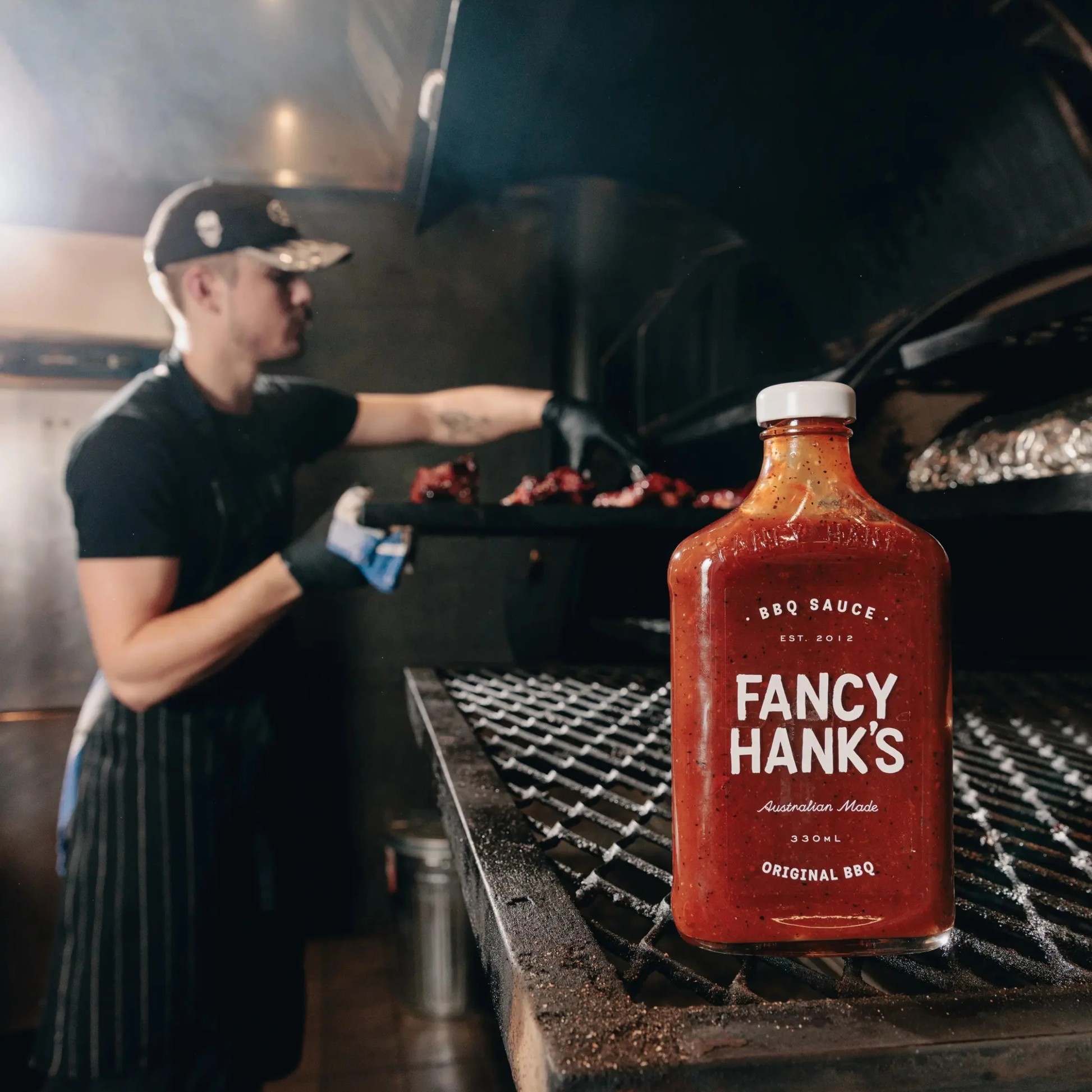 Fancy Hanks Original BBQ Sauce 330ml on a grilling rack, which is a slow-cooked American style barbecue sauce that is tangy, rich and molasses layered depth.