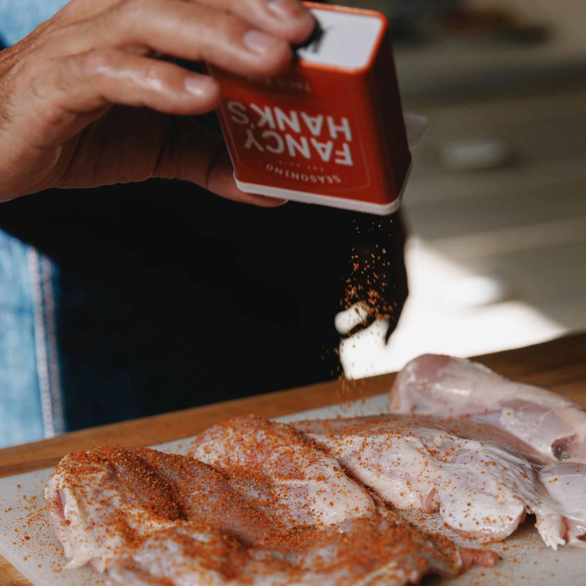 A person seasoning the chicken using the Fancy Hanks Taco Rub 90g in to a bowl, a bold vegan friendly spice blend for tacos, and anything that needs a flavour hit. No preservatives added.