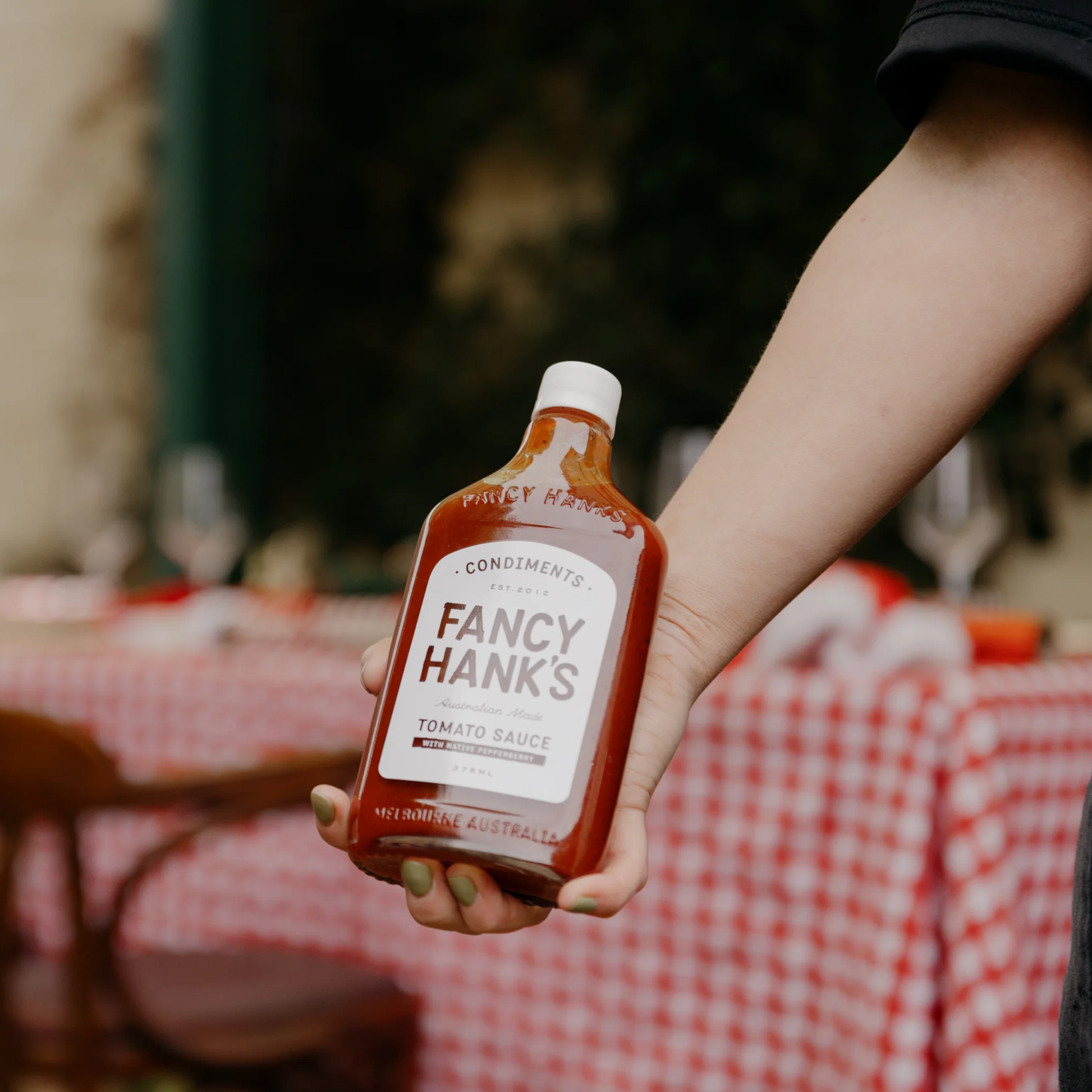 Showing the Fancy Hanks Tomato Sauce 330ml hand held, a classic Australian tomato sauce with Australian-grown tomatoes, malt vinegar and Tasmanian Mountain Pepper.