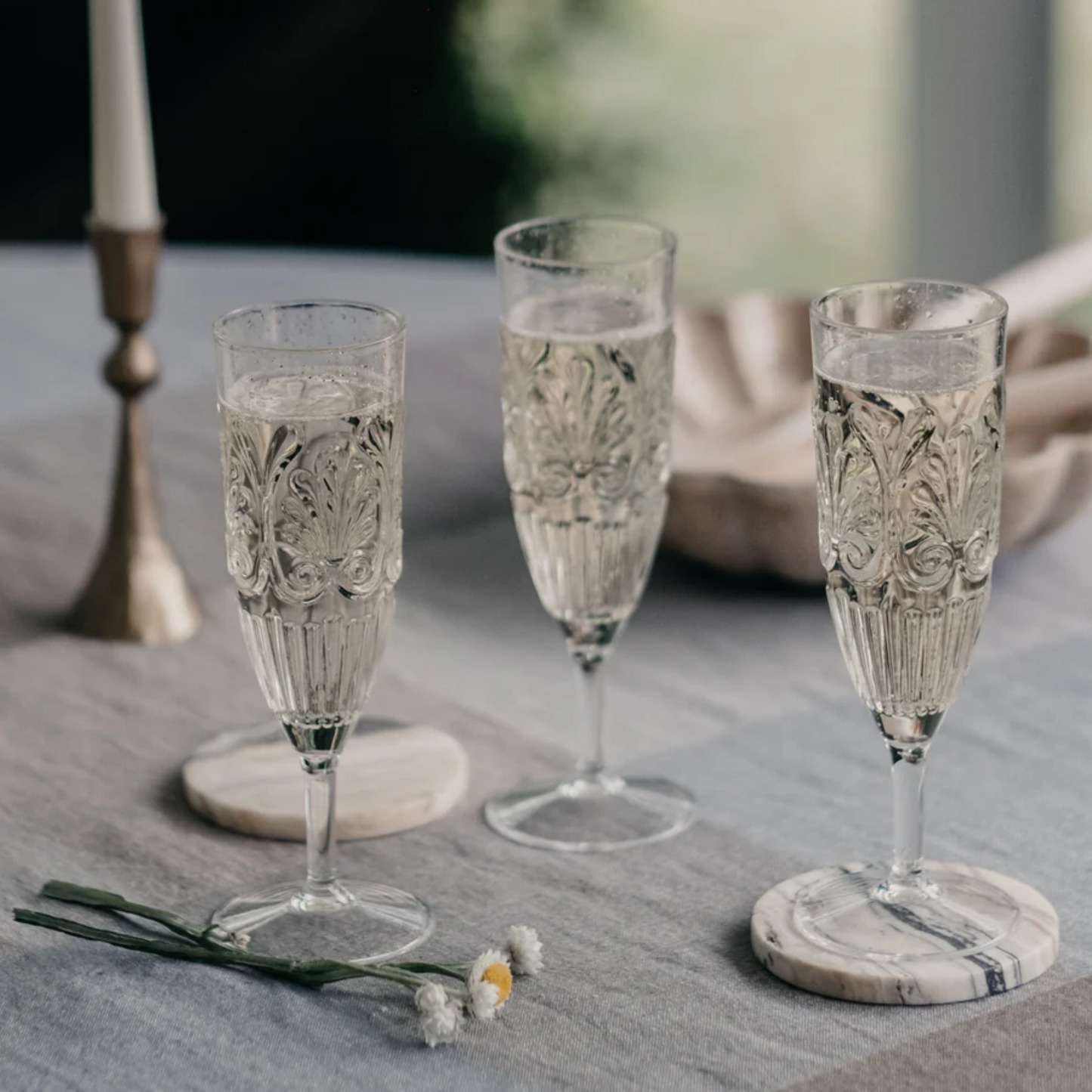 Three glasses on a table Clear acrylic champagne flute with elegant embossed detailing, glass-like clarity, and shatter-resistant BPA-free material.