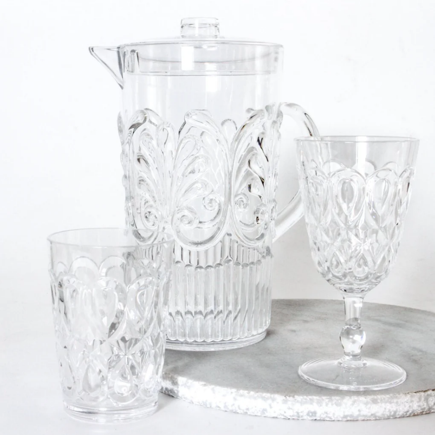 Clear acrylic jug with acrylic glassware on display on marble disc