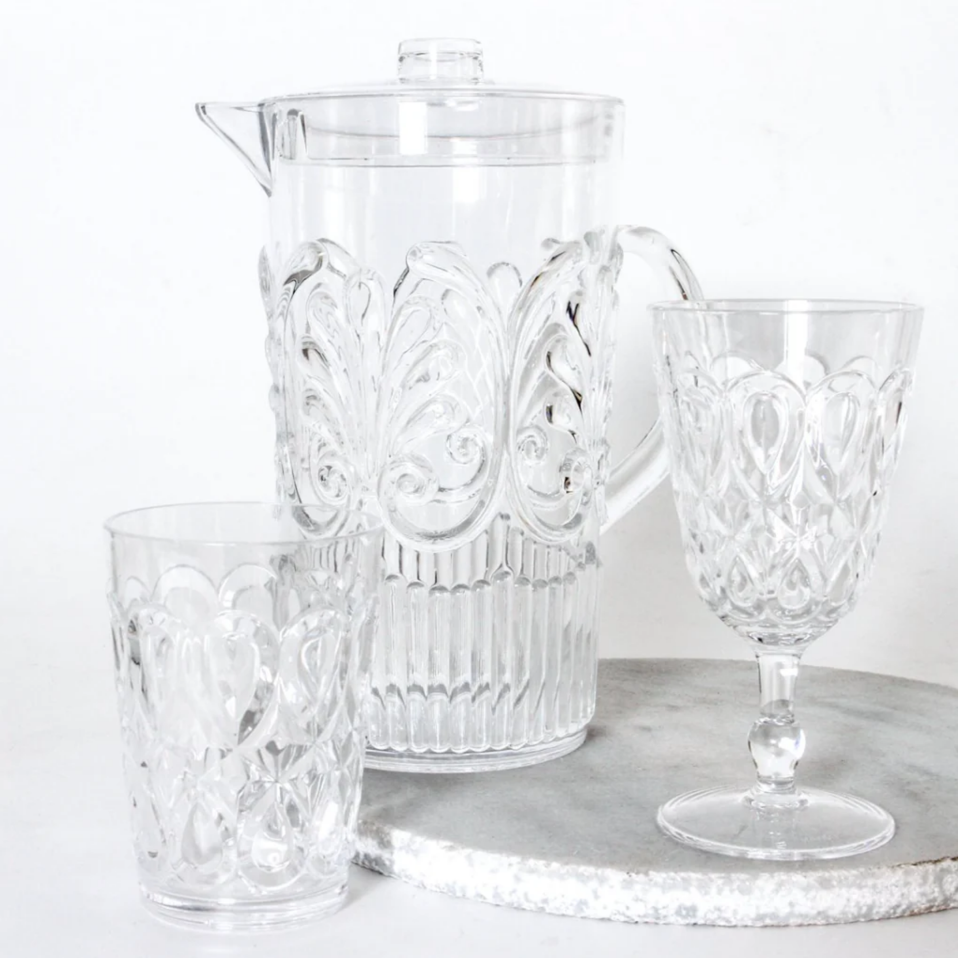 Clear acrylic jug with acrylic glassware on display on marble disc