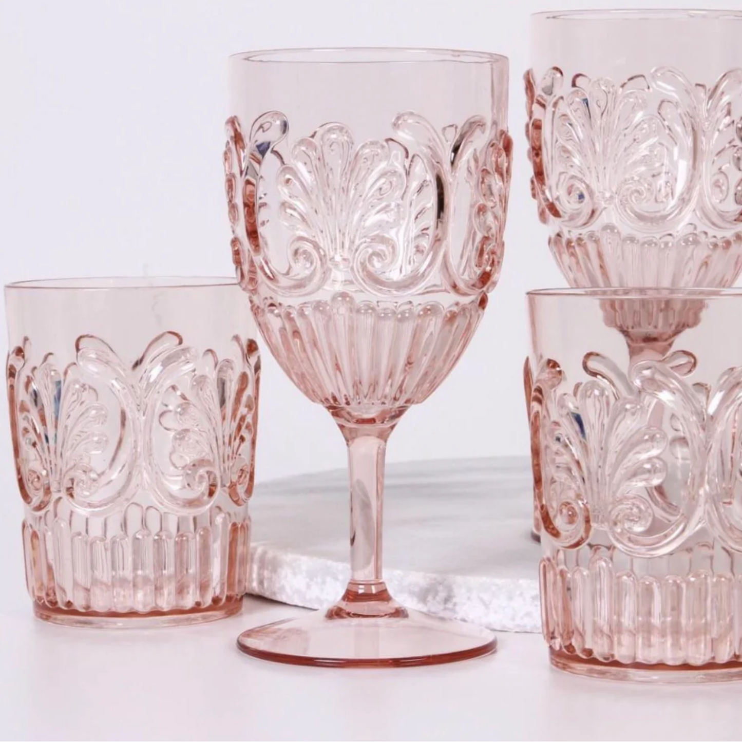 Collection of plae pink acrylic glassware on display and marble plate