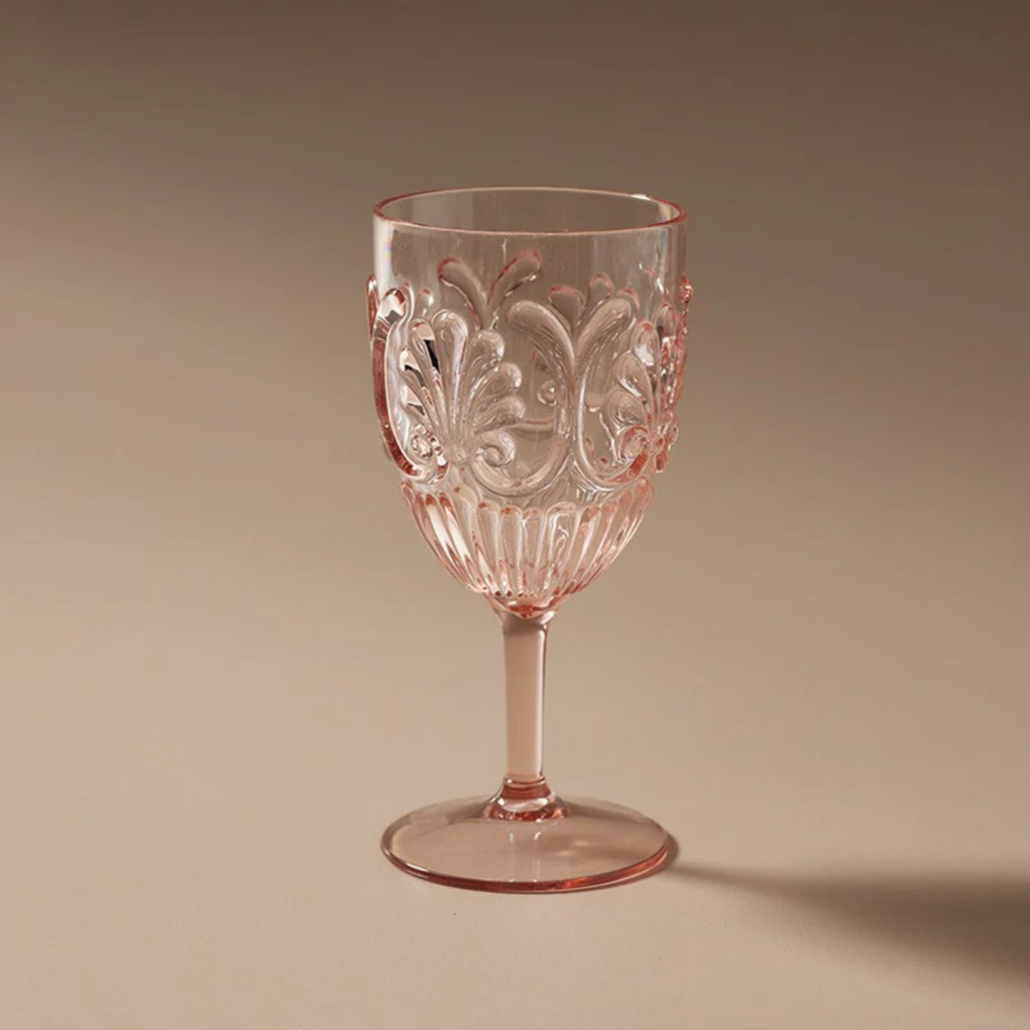On a brown background Fathom Acrylic Wine Glass Pale Pink featuring a refined shape and durable BPA-free plastic ideal for outdoor dining or special occasions.