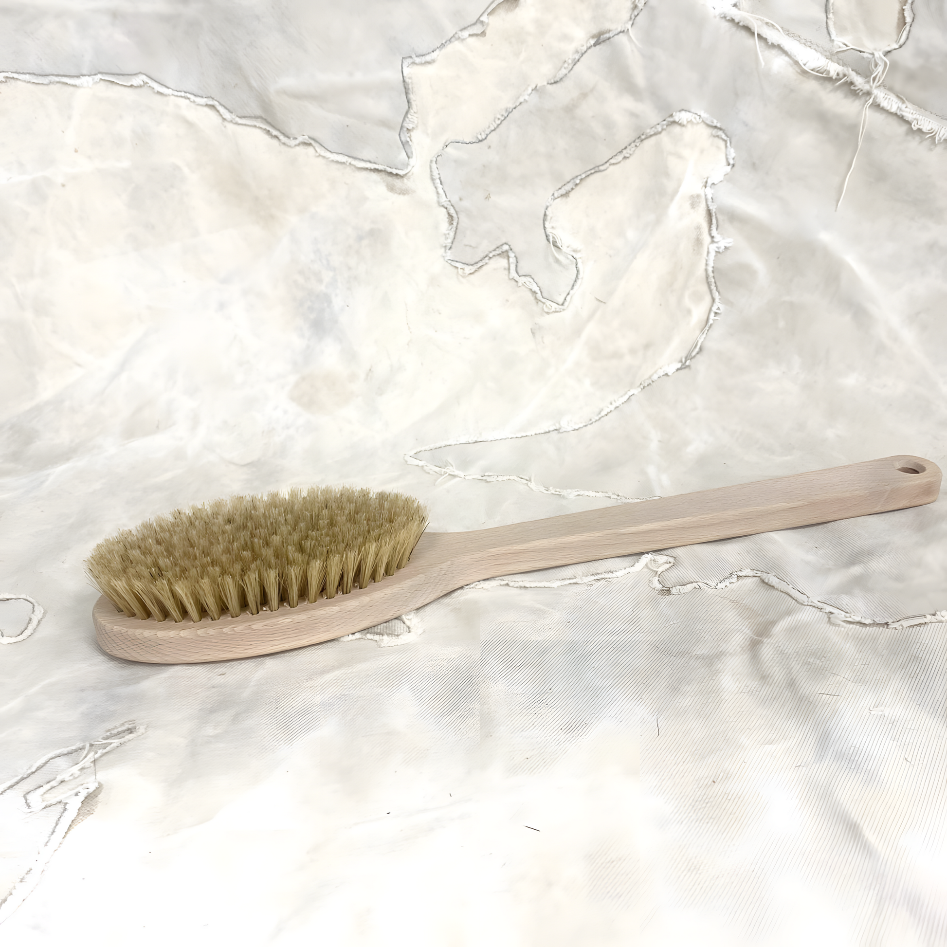 Laid on a surface, the Fathom 38cm beechwood bath brush with natural bristles, single-piece German-made bath brush for gentle skin exfoliation and cleansing in the shower.