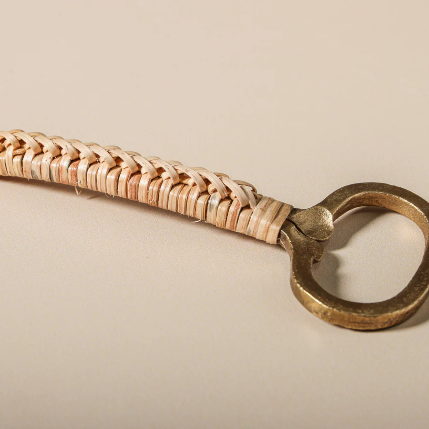 Close up of Bamboo and brass bottle opener - natural brown bamboo handle with antique brass iron accents; handcrafted, 13 cm long, elegant and functional bar or kitchen accessory.