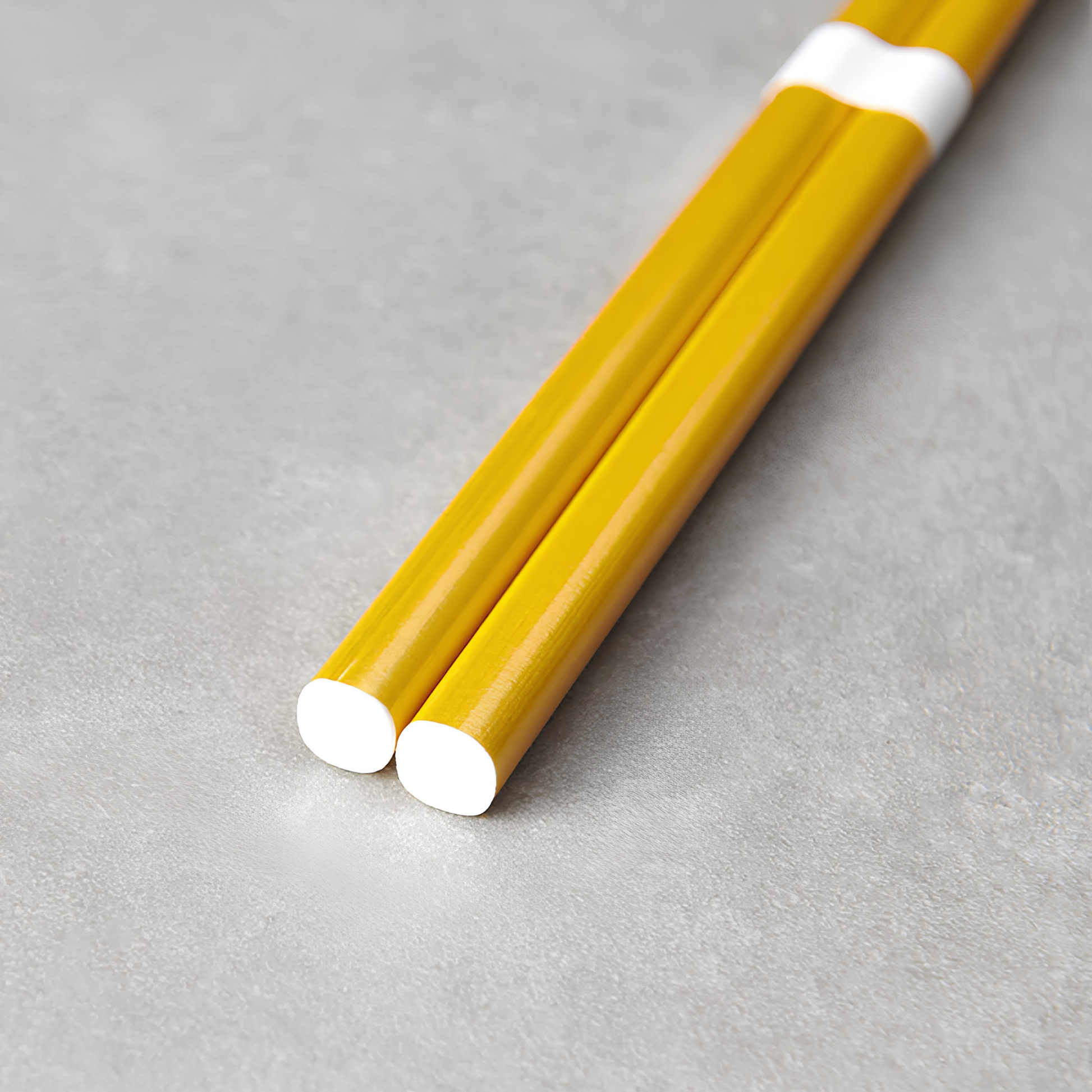 Close up on the bottom part of the Fathom Chopsticks Pair Lacquered Gold, sleek finish with a white accent.