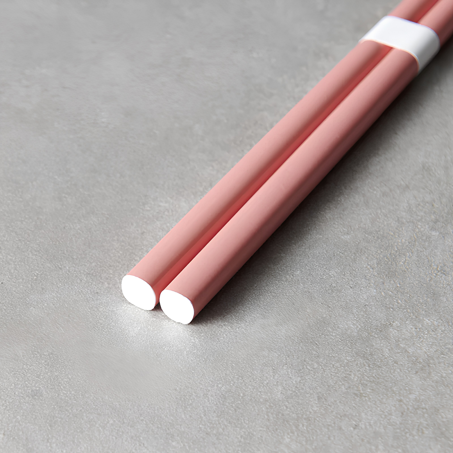 Close up on the bottom part of the Fathom Chopsticks Pair Lacquered Pink, soft finish with sleek white accent.
