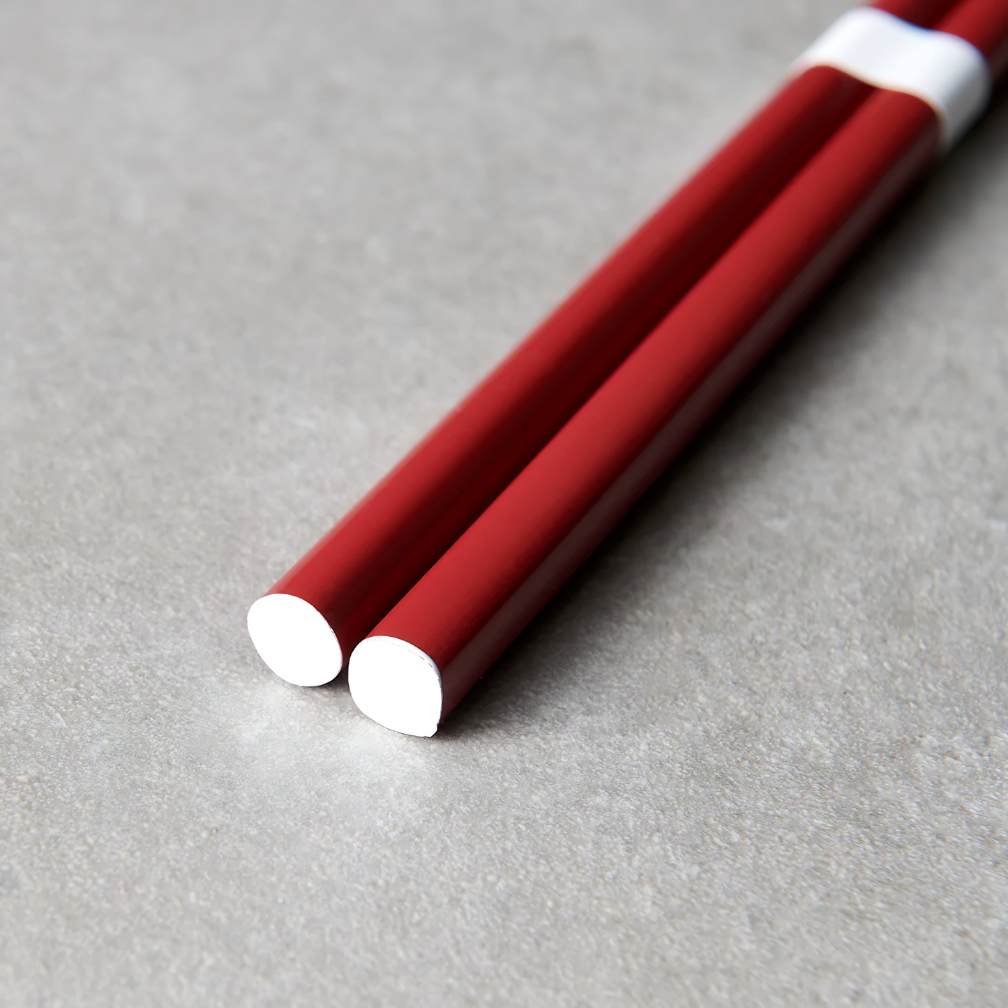 Close up on the bottom part of the Fathom Chopsticks Pair Lacquered Red deep finish with white accent.