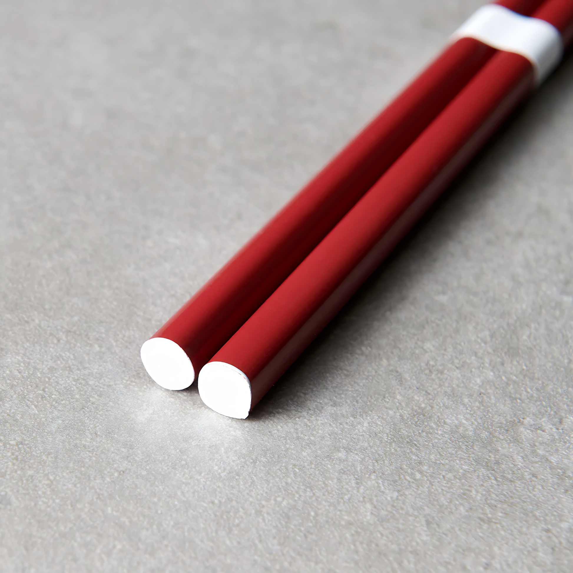 Close up on the bottom part of the Fathom Chopsticks Pair Lacquered Red deep finish with white accent.