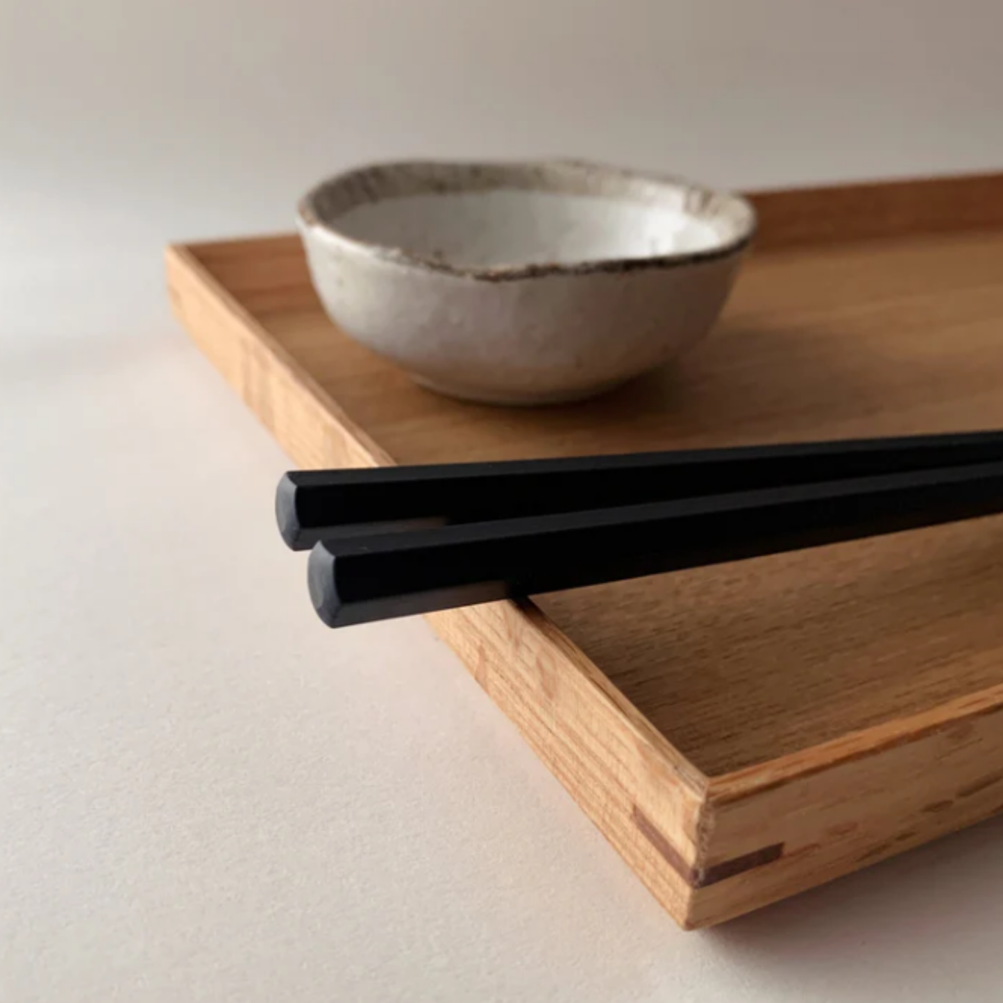 Close up of the bottom part of the chopsticks from Fathom Kyoto Chopsticks Set of 5 - Timber-tone resin chopsticks, 23cm long, hexagonal shape with matte finish for non-slip grip, dishwasher safe.