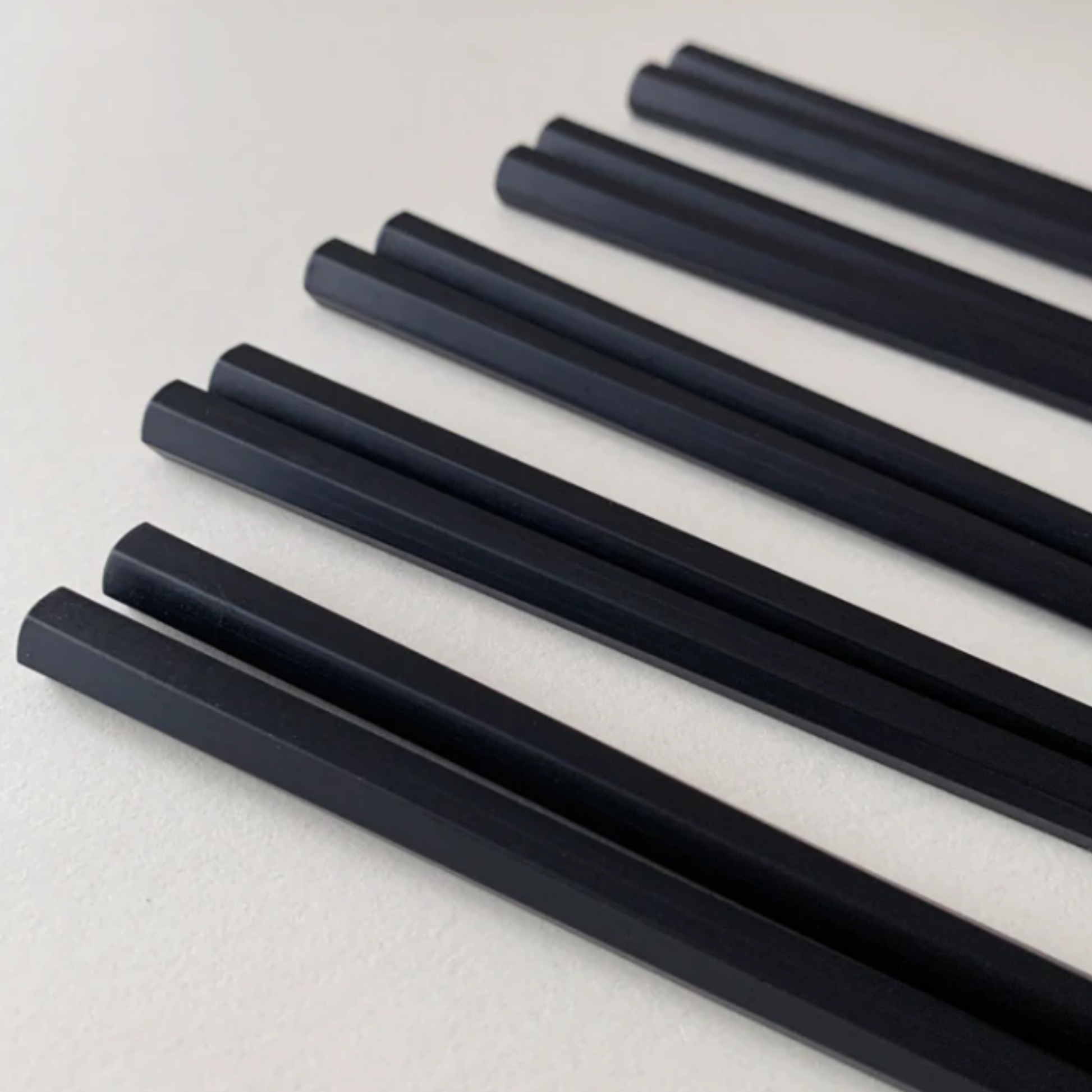 Showing the hexagonal bottom of Fathom Osaka Chopsticks Set of 5 - Black resin chopsticks, 23cm long, hexagonal shape with matte non-slip finish, comfortable grip, dishwasher safe.