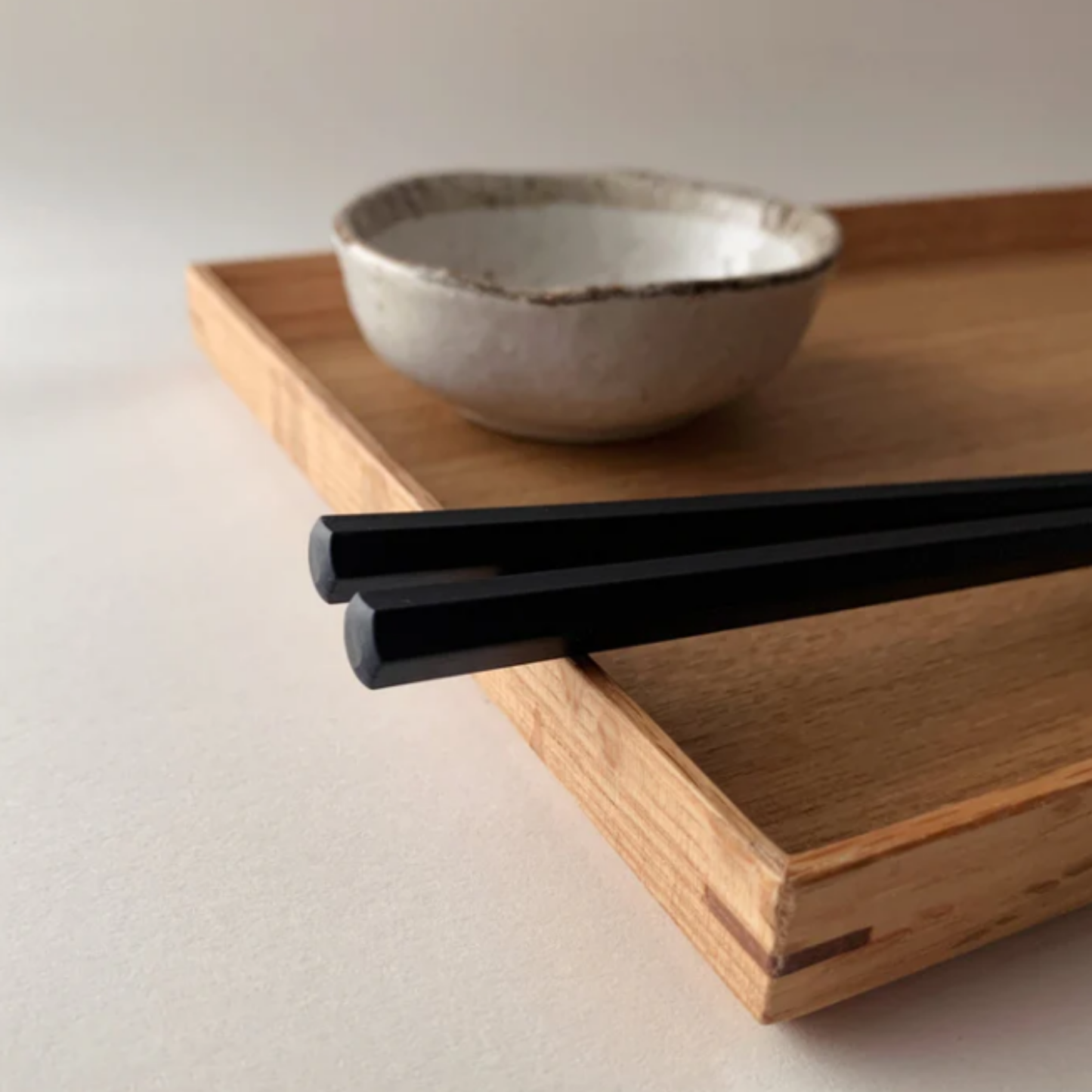 Upclose of the hexagonal bottom of the pair of chopsticks from Fathom Osaka Chopsticks Set of 5 - Black resin chopsticks, 23cm long, hexagonal shape with matte non-slip finish, comfortable grip, dishwasher safe.