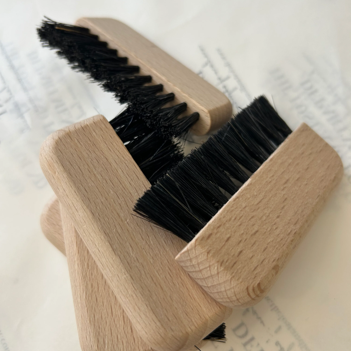 Five Fathom Computer Brushes with black bristles are stacked together on a white surface with faint text in the background.