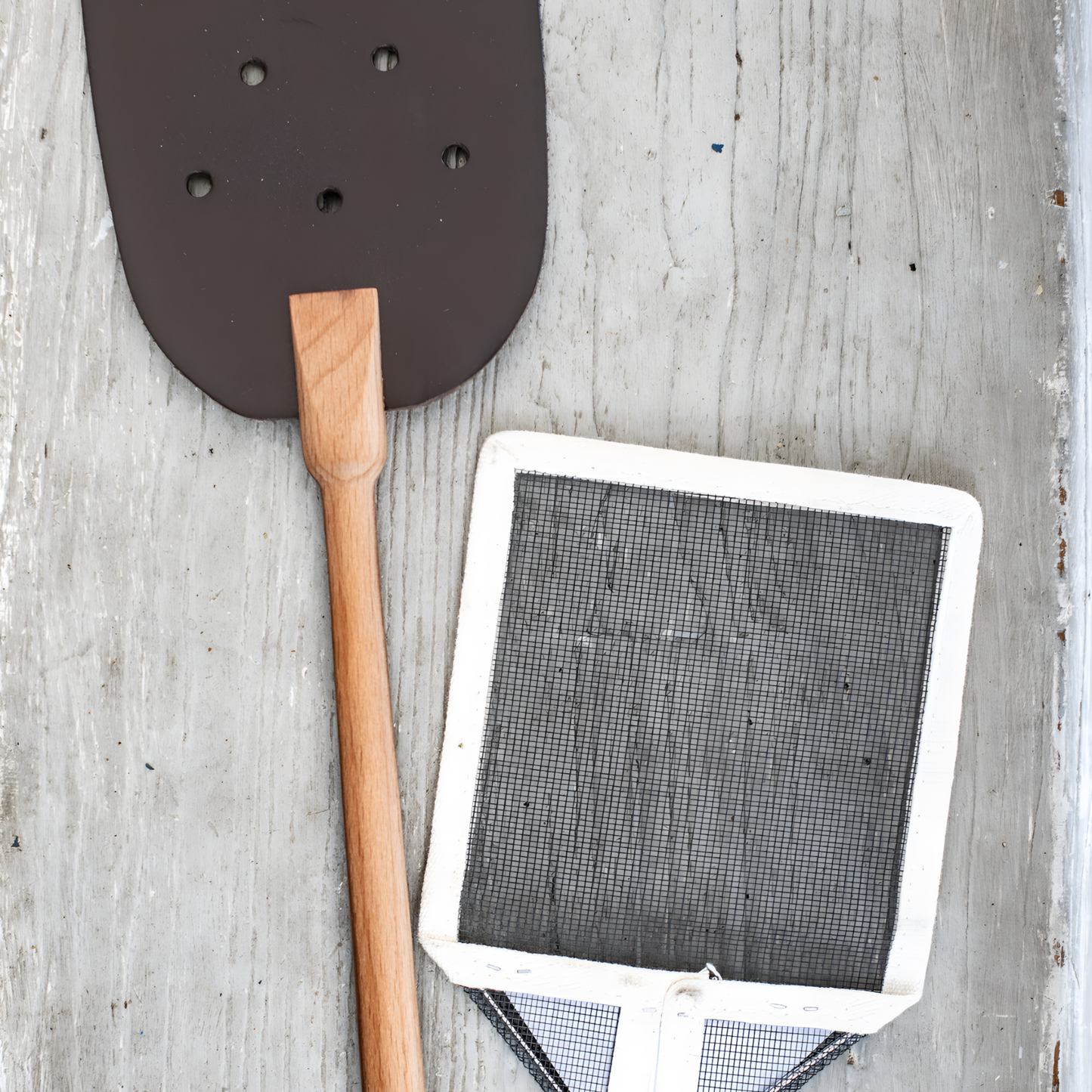 Seen with another type of swatter the back view of Fathom French mesh fly swatter with natural handle, 54cm lightweight insect control tool for indoor and outdoor use in kitchens, patios, and dining areas.