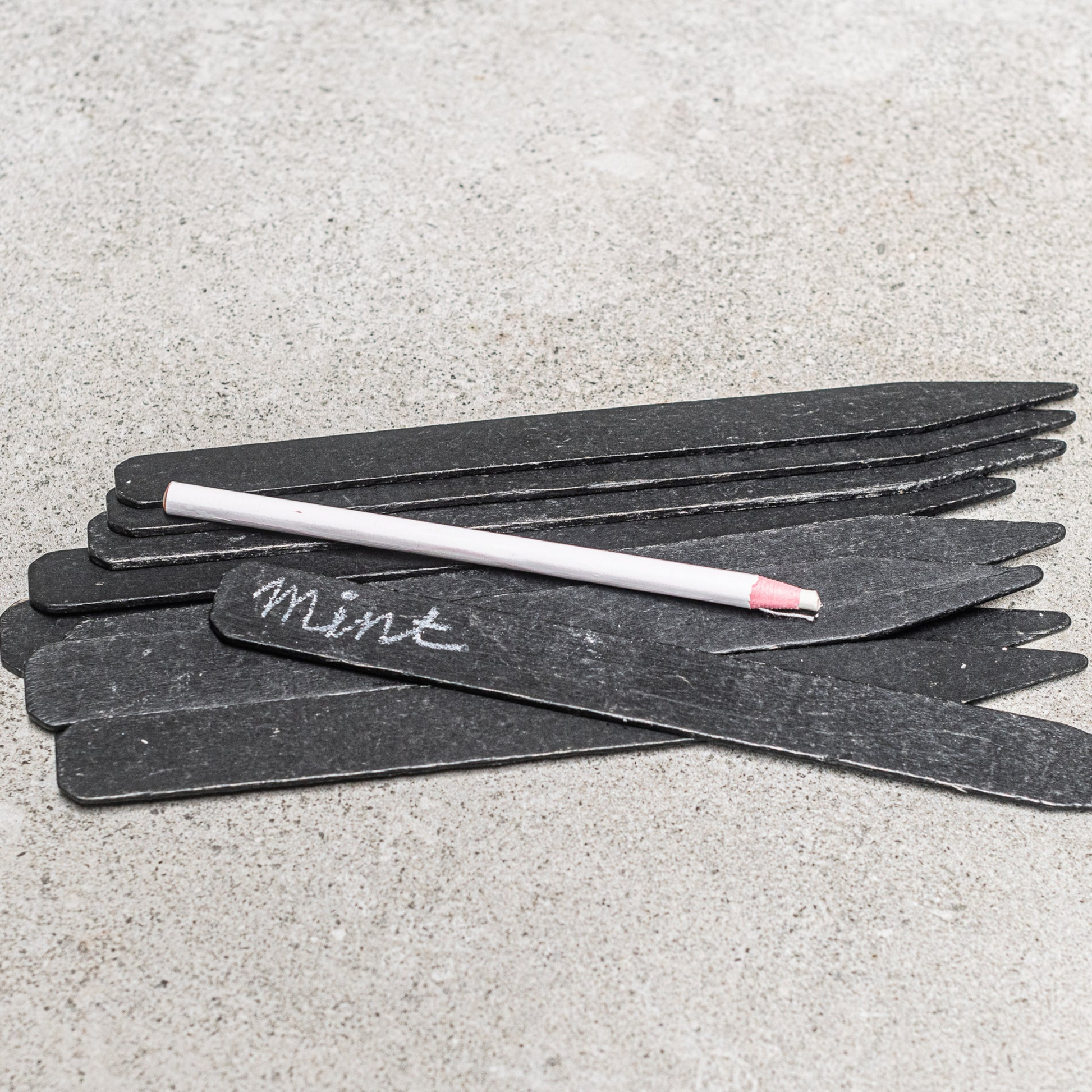Black garden lables with white pencil sprawled out on concrete bench