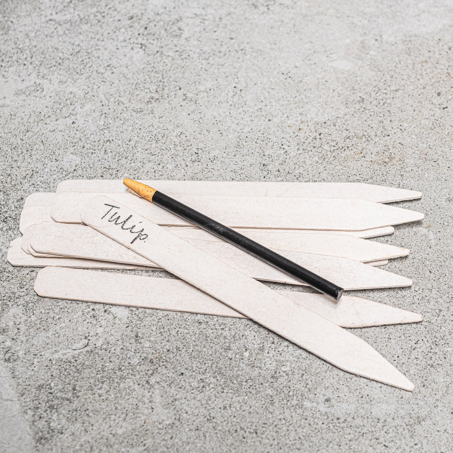 White garden lables with black pencil sprawled out on concrete bench