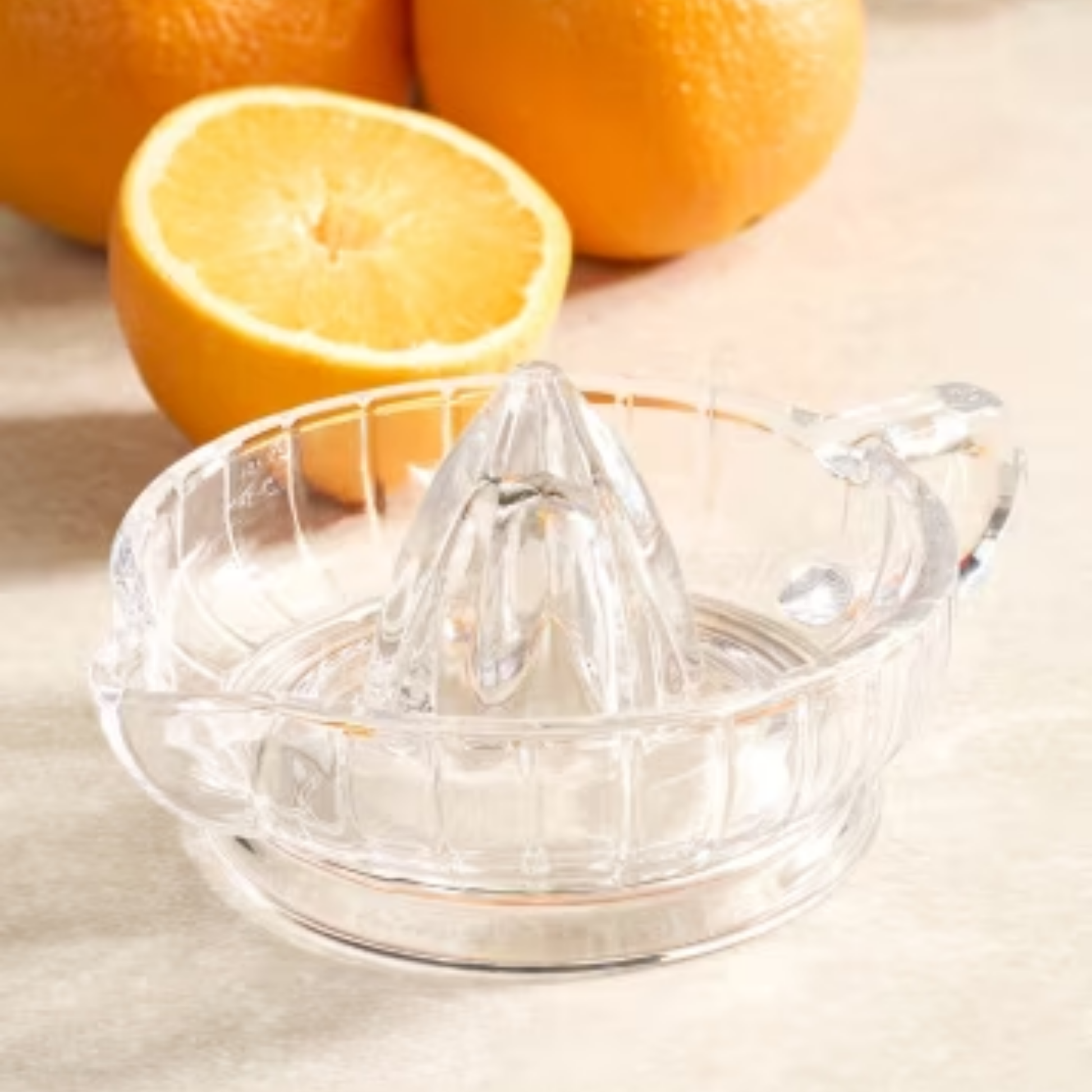 Close up of glass citrus juicer infront of oranges