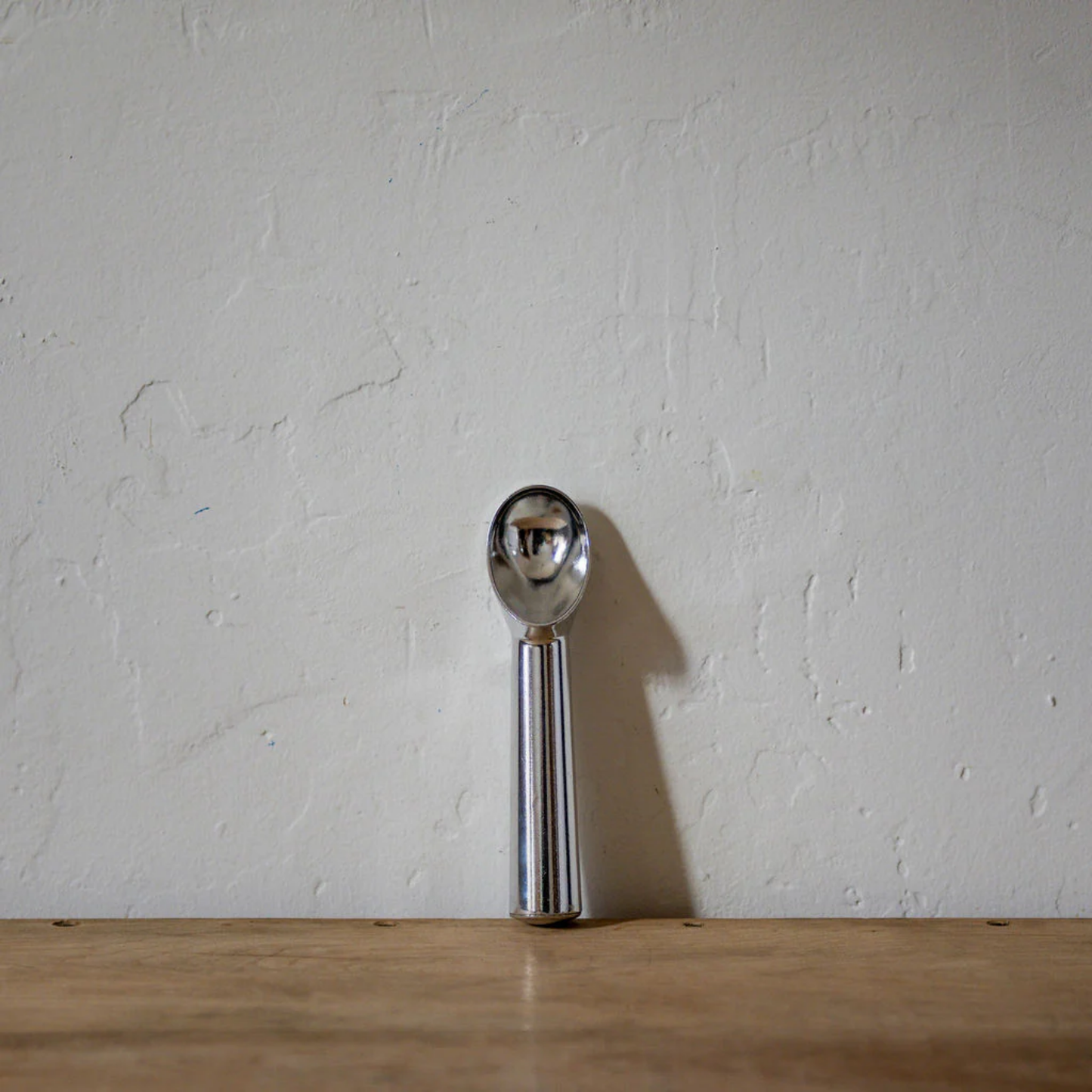 Aliminium ice cream scoop front view on wooden countertop