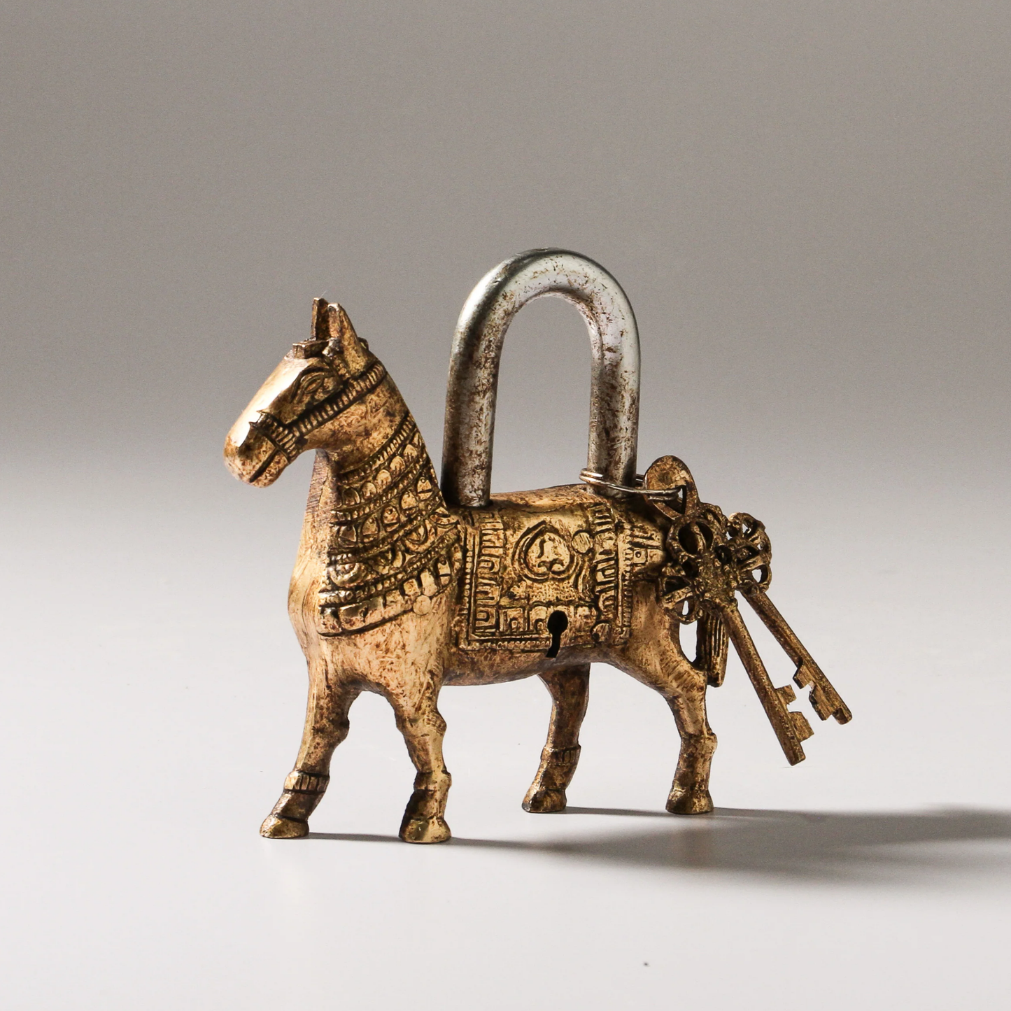 Indian brass horse padlock with keys front angled view on grey backdrop