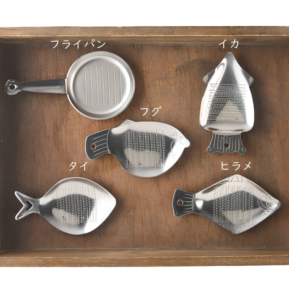 Fathom Japanese Mini Squid Grater White Ceramic, squid-shaped design for grating small amounts of salt, ginger, and wasabi, etc. Shown on a tray with other fish grater and fry pan.