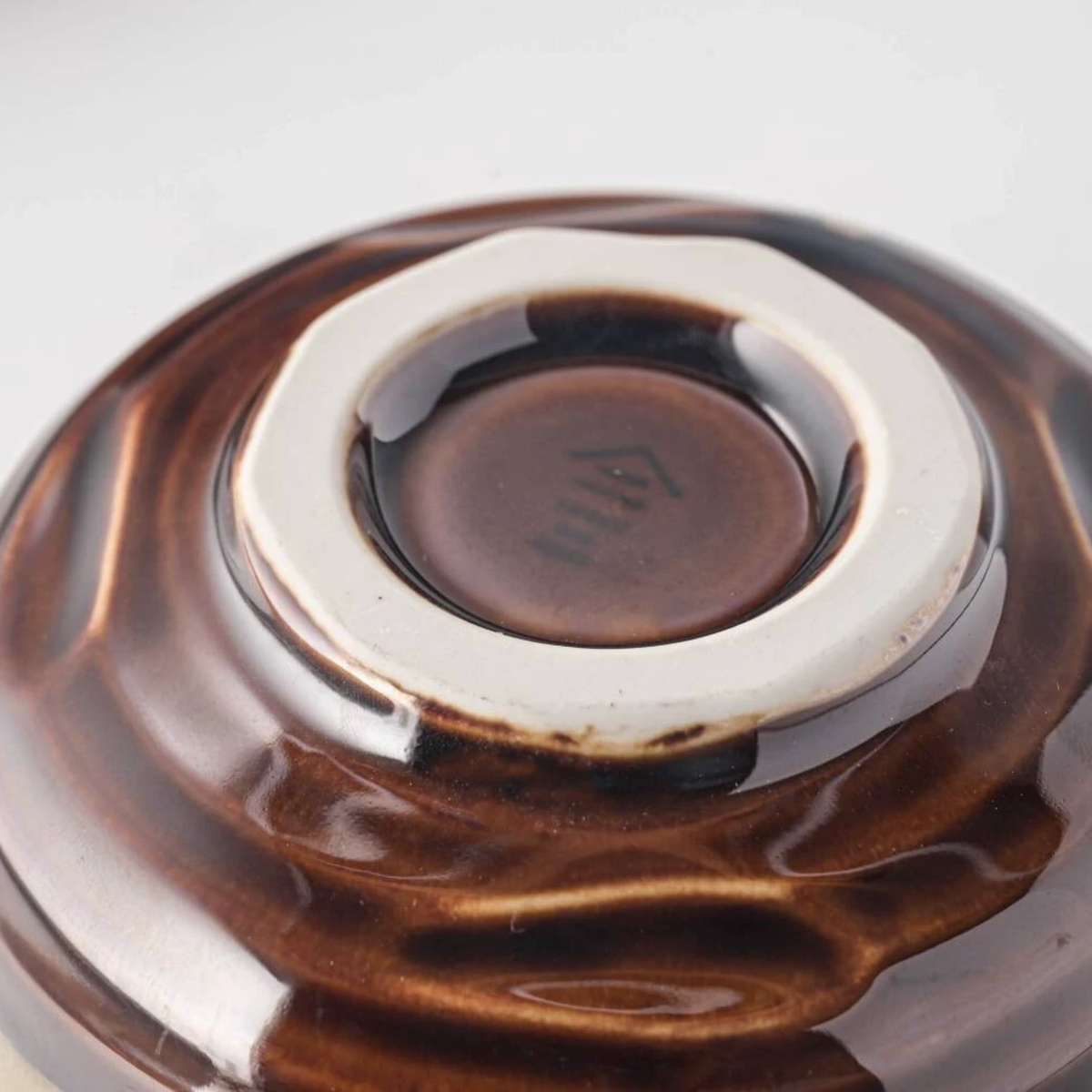 Bottom view of the bowl that is the Fathom Japanese Mino Ware Matcha Bowl Miyajima Amber Ceramic, hand-crafted with a rich, lustrous glaze.