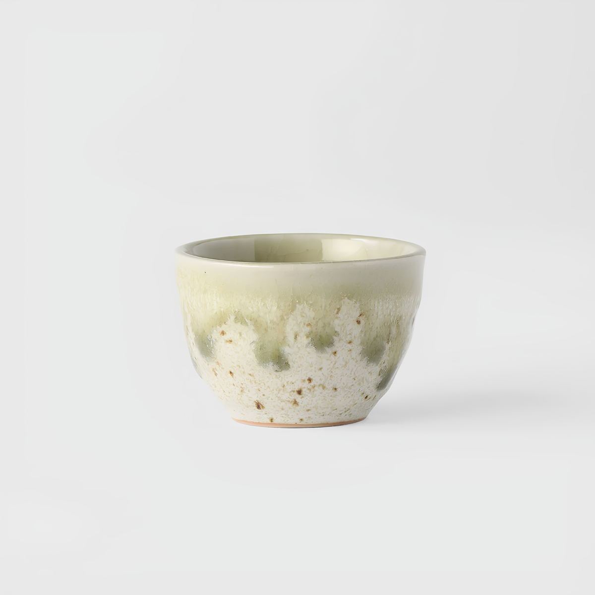 Side view of Fathom Japanese Sake Cup in light green and cream, handcrafted ceramic with drip glaze, rounded shape and 30ml serving capacity.