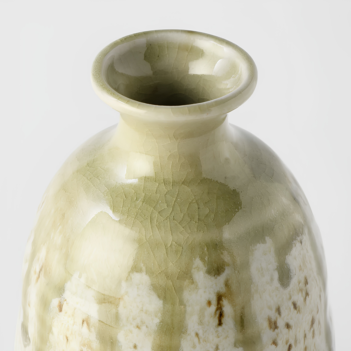 Close up semi top view of Fathom Japanese Sake Jug in light green, ceramic with drip glaze, rounded body and narrow neck for smooth pouring.