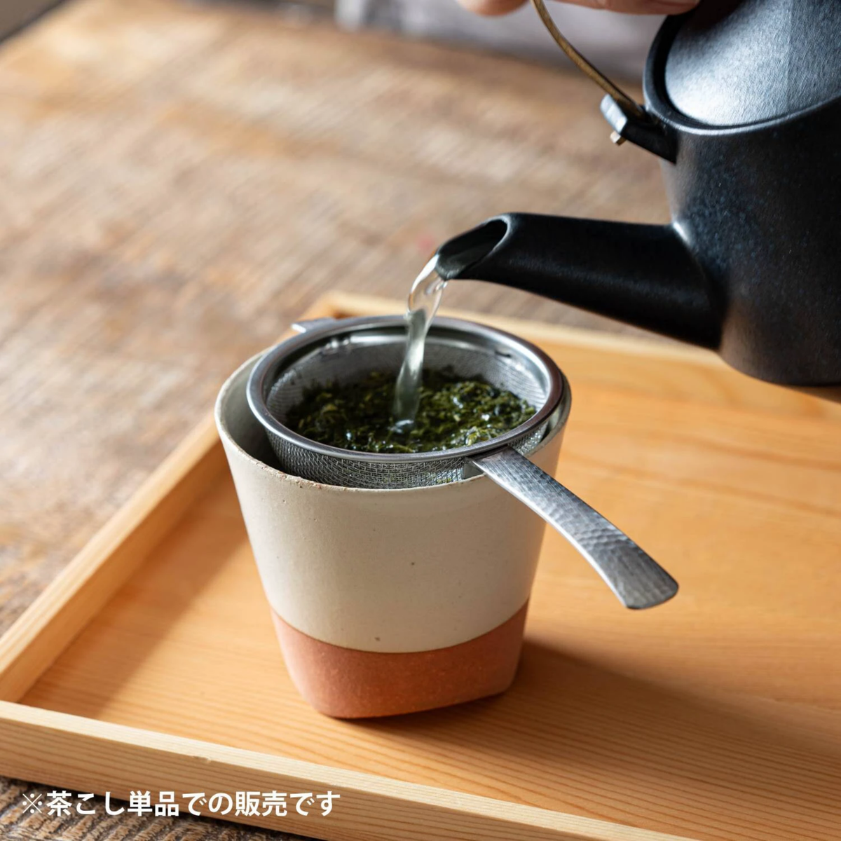 Fathom Japanese Tea Strainer Silver Stainless Steel, flat design strains tea leaves and matcha powder, shown with matcha on top of a cup while being poured with hot water.