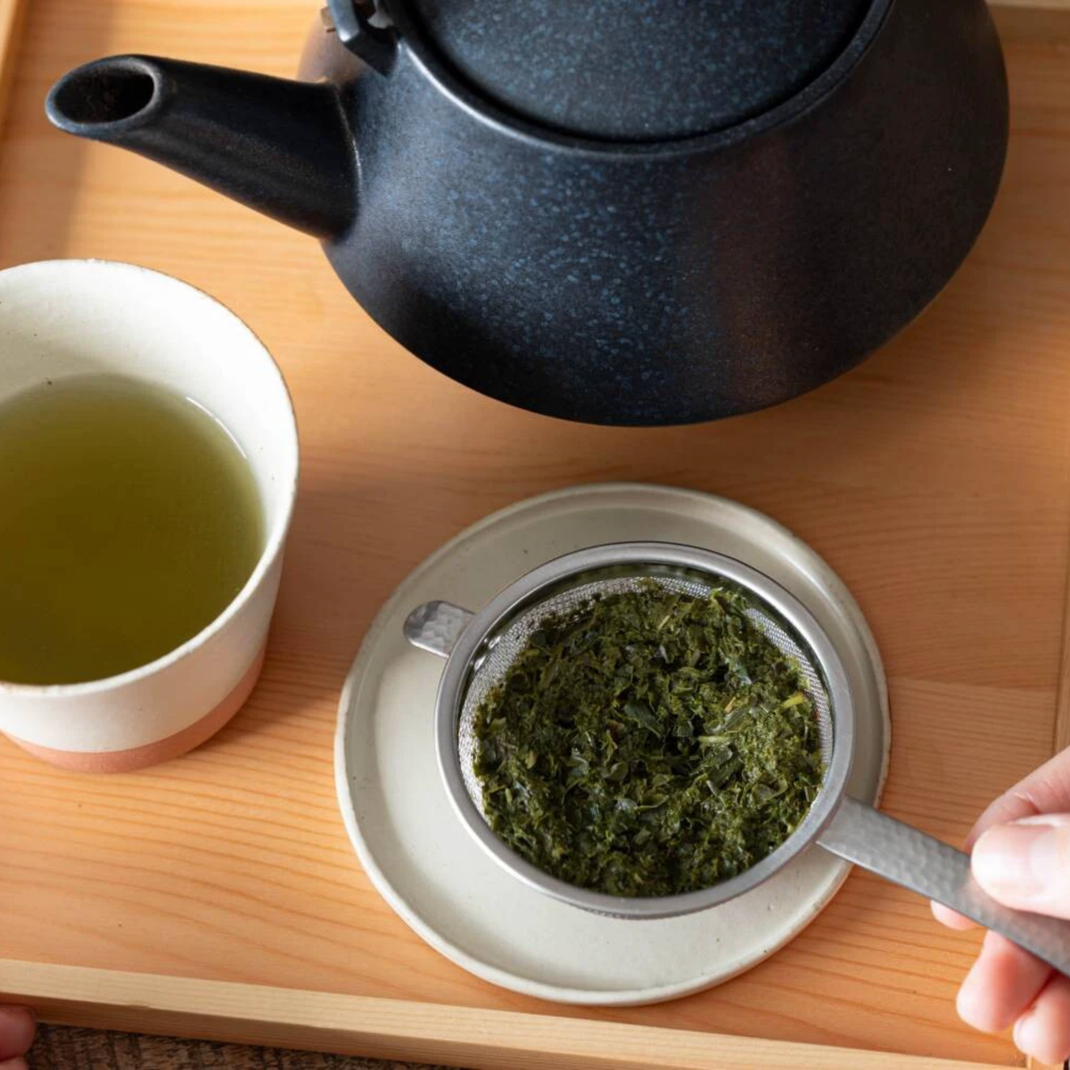 Fathom Japanese Tea Strainer Silver Stainless Steel, flat design strains tea leaves and matcha powder, shown on a little circle tray.