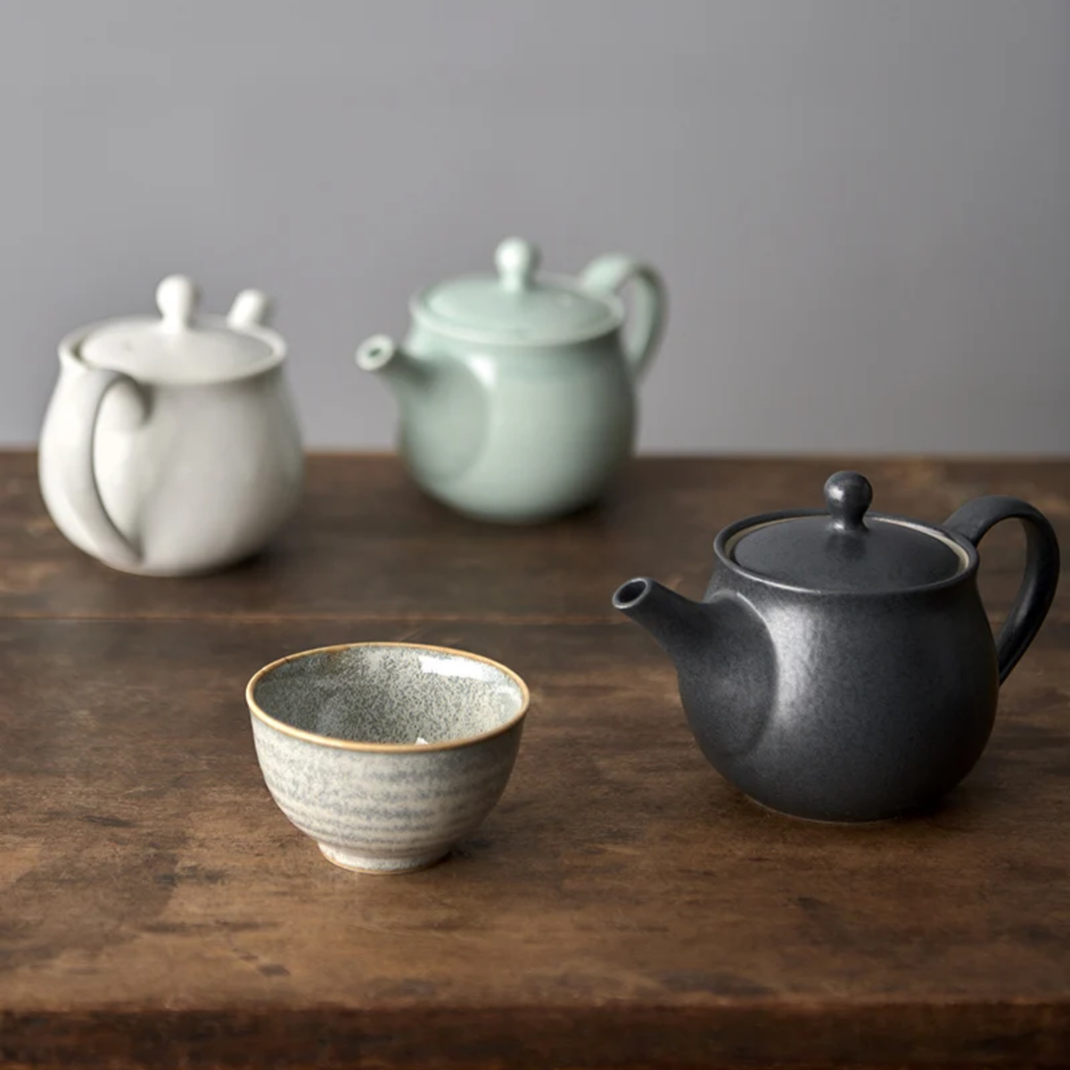 Showing the white and black teapot with the Fathom Japanese Teapot in light green, ceramic with smooth Tomei glaze, 400ml capacity and balanced form for smooth pouring.
