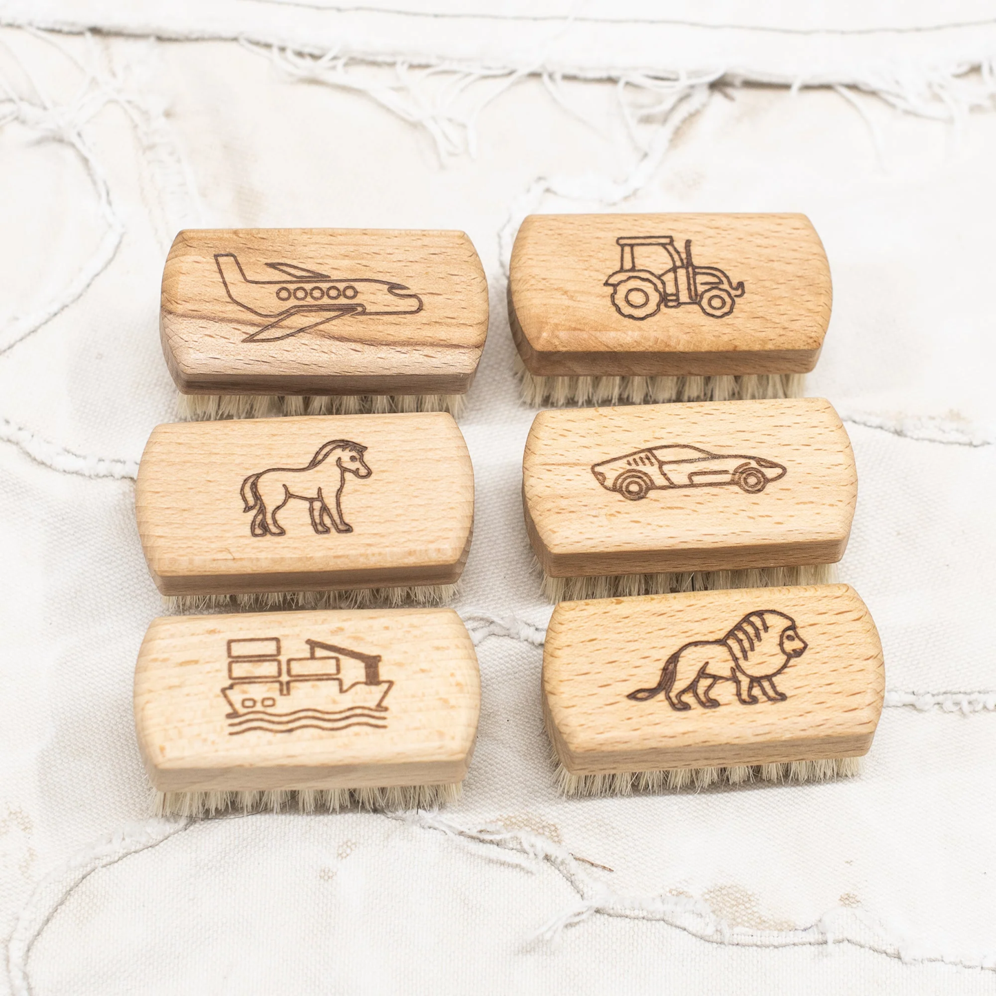Children's nail brushes by Fathom, made from beechwood with soft bristles and wooden handle with engraved plane, tractor, pony, car, boat and lion.