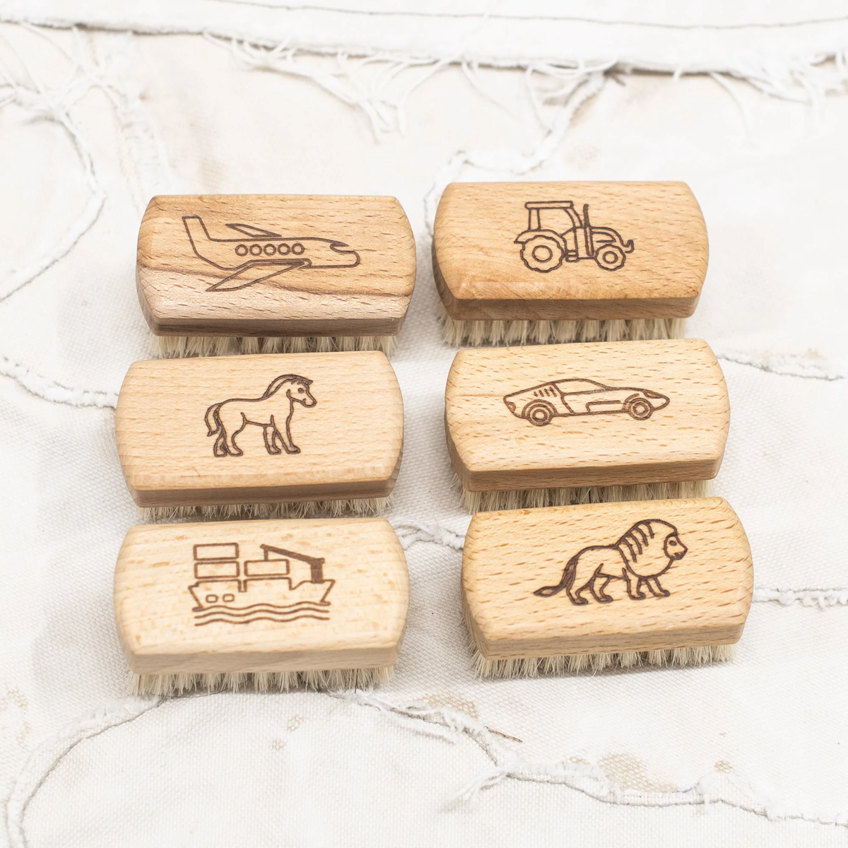 Children's nail brushes by Fathom, made from beechwood with soft bristles and wooden handle with engraved plane, tractor, pony, car, boat and lion.