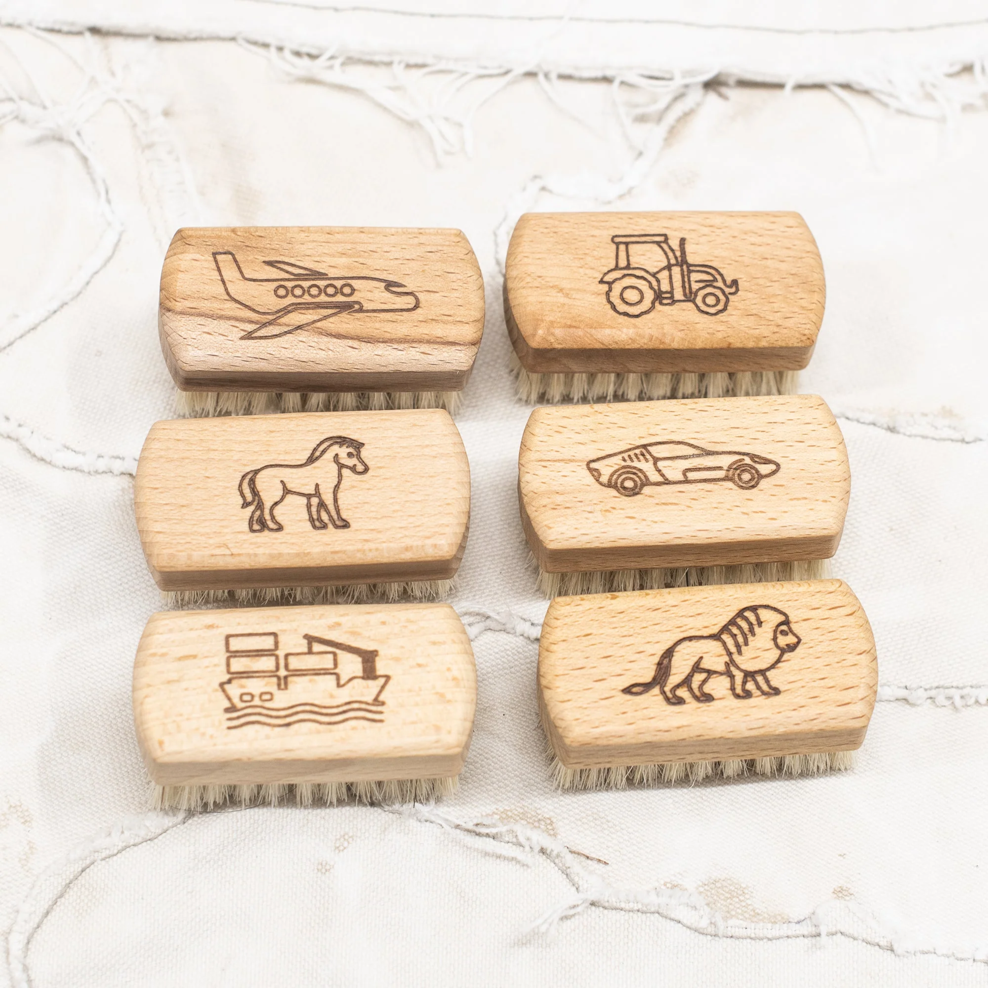 Children's nail brushes by Fathom, made from beechwood with soft bristles and wooden handle with engraved plane, tractor, pony, car, boat and lion.
