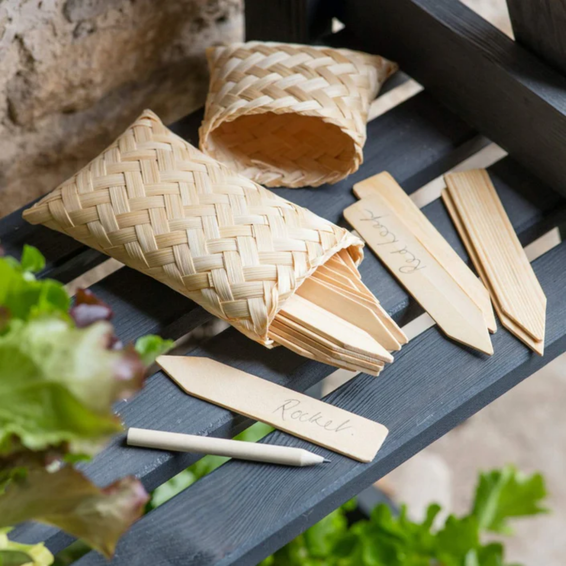 Bamboo bag containing gardening labels and pencil on wooden bench outside