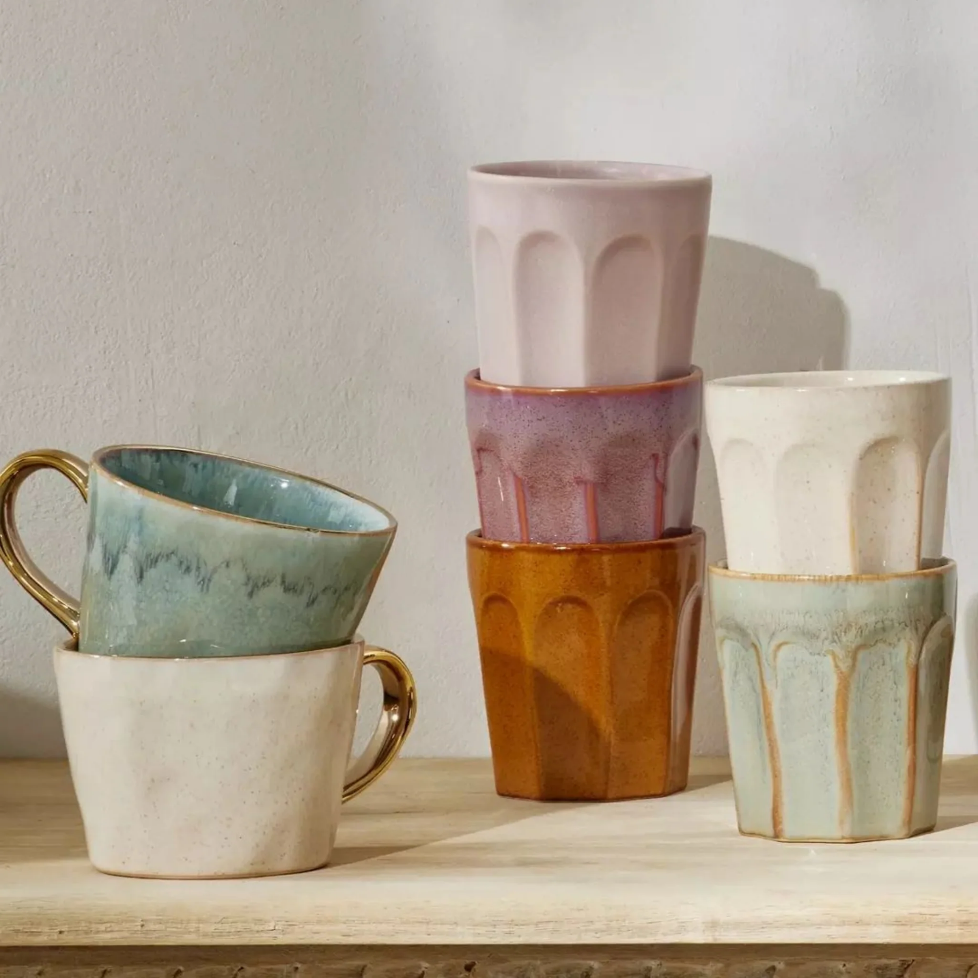 Collection of latte mugs all stacked together on wooden counter top