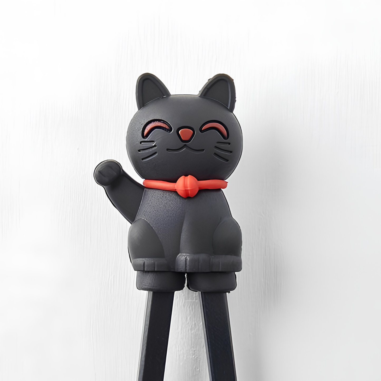 Close up on the Lucky cat from Fathom Maneki Kids Chopsticks Black connected to the top for beginners to master using chopsticks.