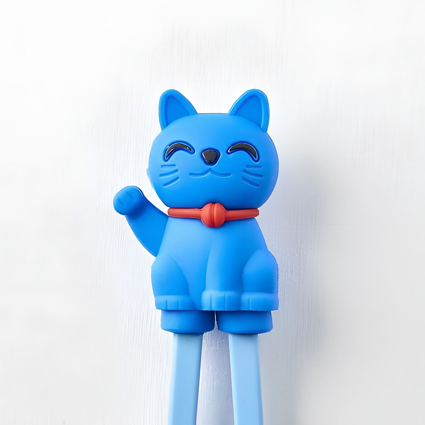 Close up on the Lucky cat from Fathom Maneki Kids Chopsticks Blue connected to the top for beginners to master using chopsticks.