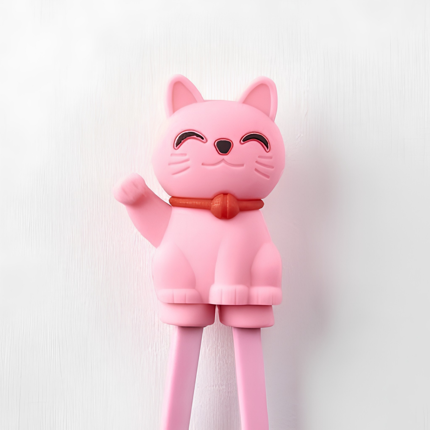 Close up on the Lucky cat from Fathom Maneki Kids Chopsticks Pink connected to the top for beginners to master using chopsticks.