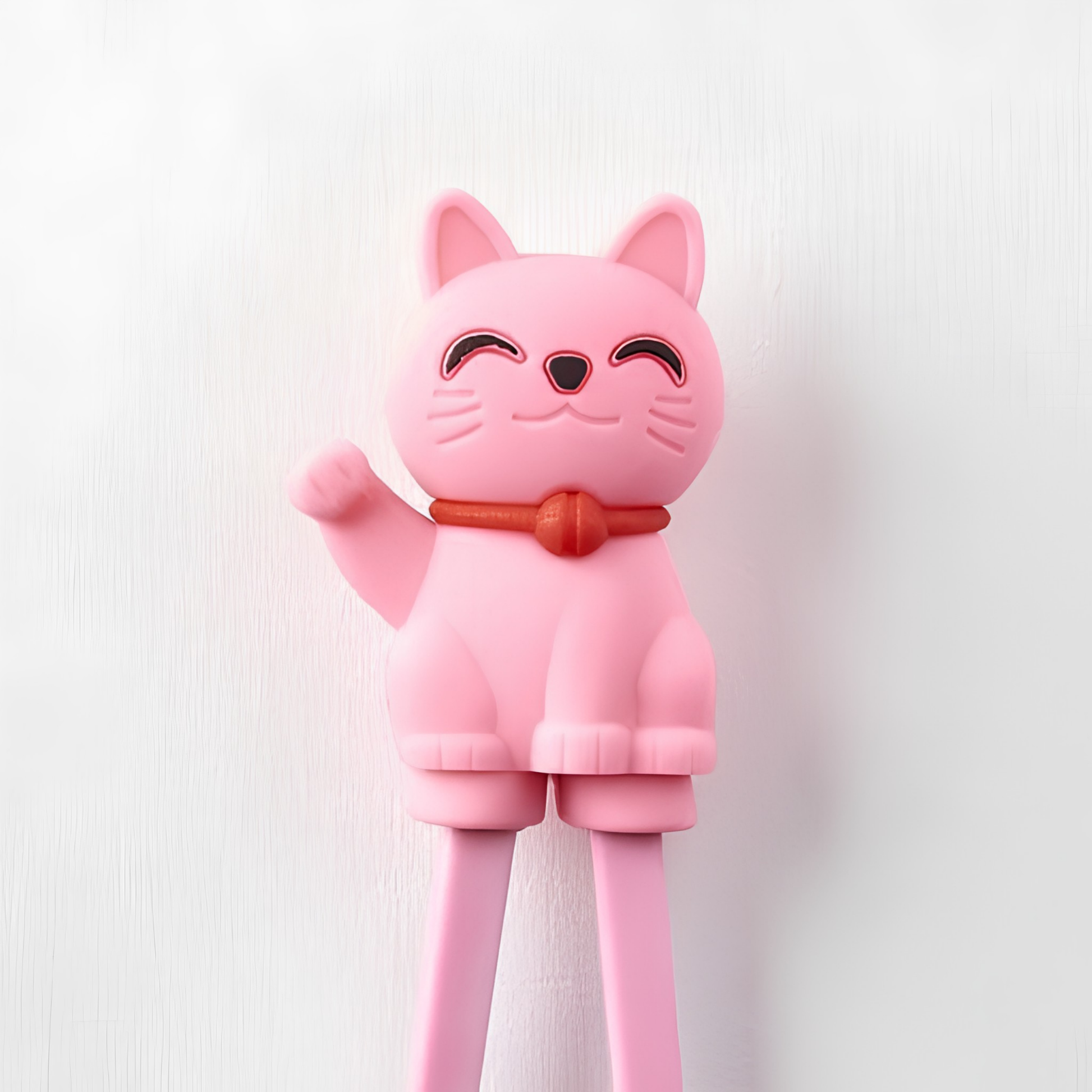 Close up on the Lucky cat from Fathom Maneki Kids Chopsticks Pink connected to the top for beginners to master using chopsticks.