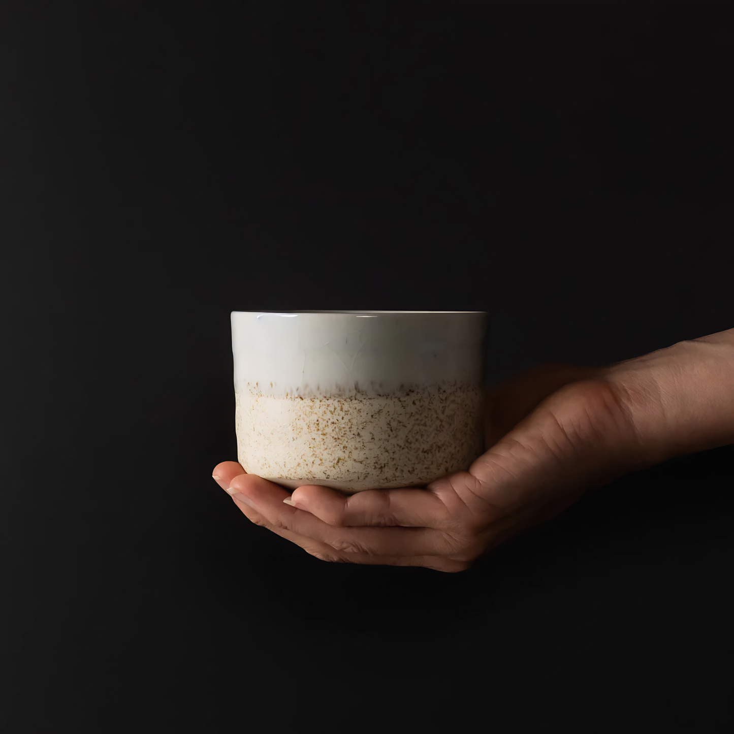 On top of a hand the side view of the Fathom Matcha Tea Bowl 10cm Aozora Fleck features a calming blue-white gradient with delicate flecked detail.