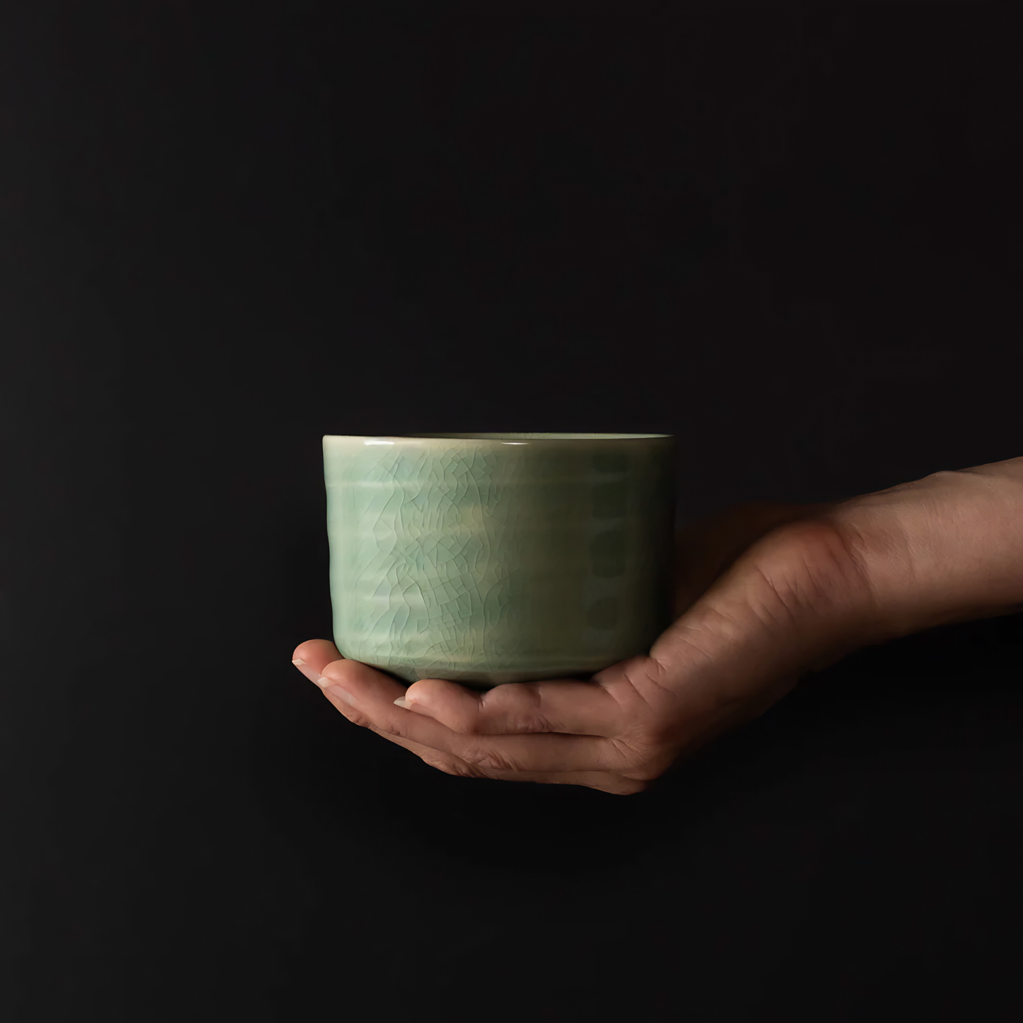 On top of a hand the side view of the Fathom Matcha Tea Bowl 10cm Jade wit glaze that is smooth, glossy soft green with gentle natural colour.