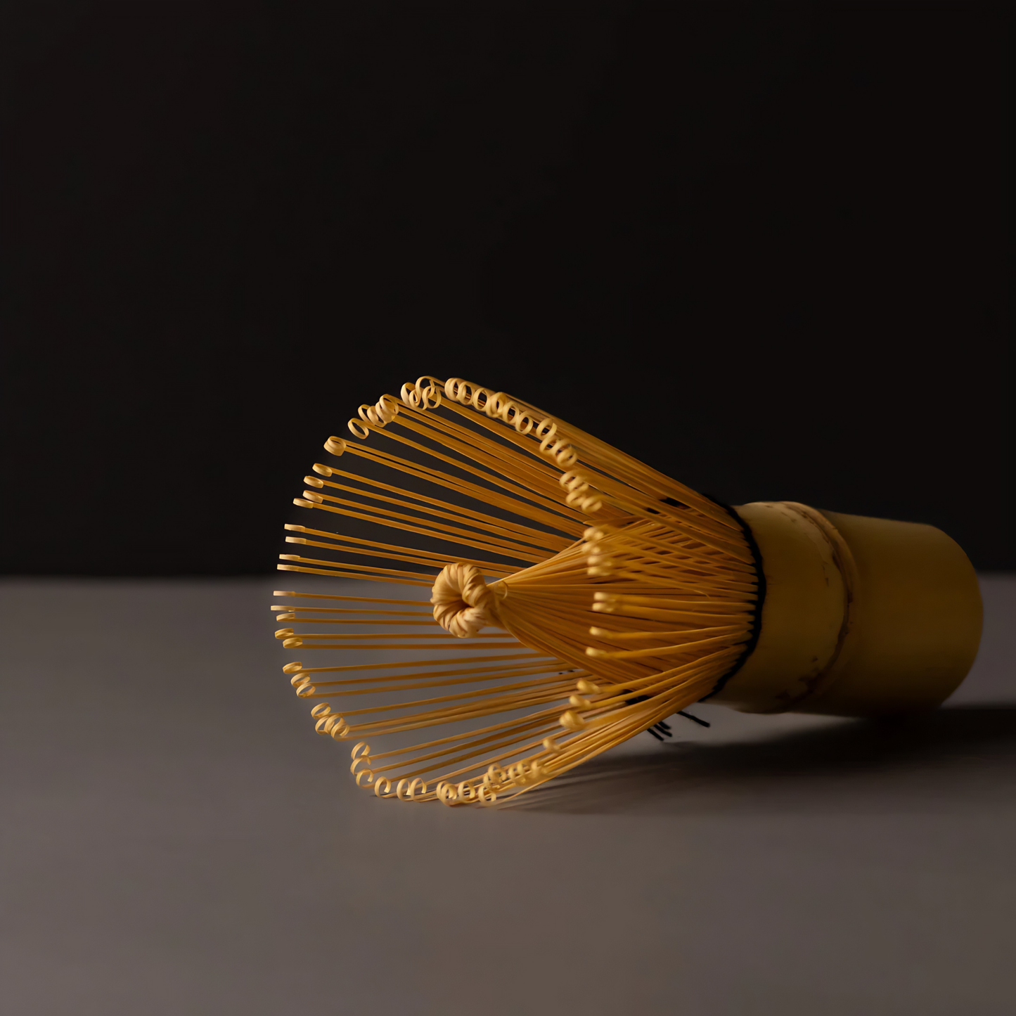 Close up laid on a surface the Fathom Matcha Whisk Bamboo 100 Prong, Chasen handcrafted from a single bamboo into delicate bristles making it as whisk