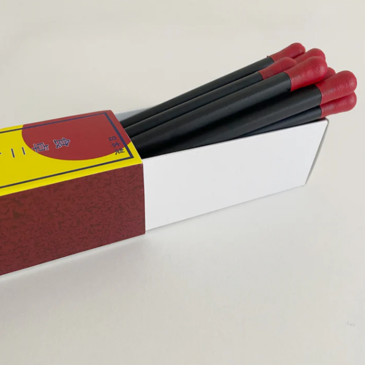 Open box with Fathom Matchstick Chopsticks Set of 5 - Red and natural resin chopsticks, 22cm long, lightweight non-slip design, dishwasher safe, in vintage-style box.