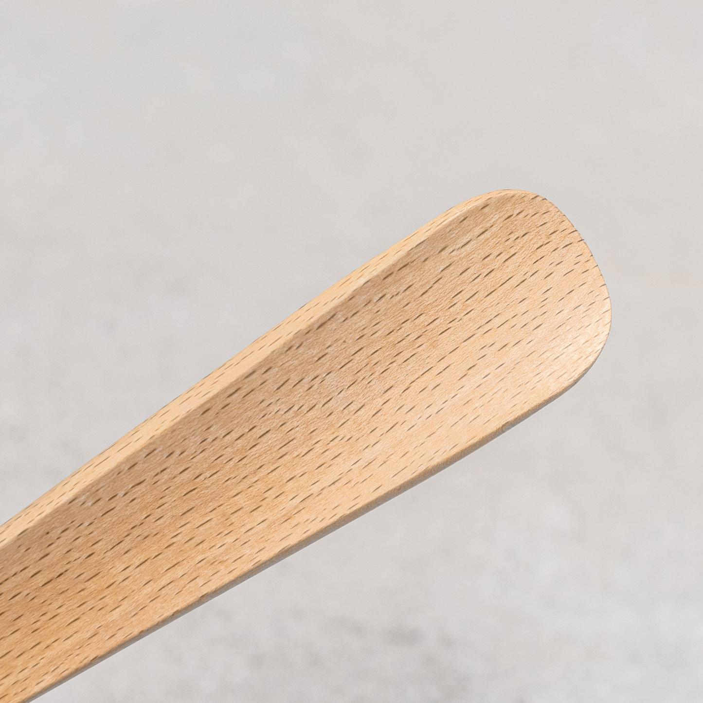 Close up on the Fathom shoe horn in a steel container, made from sustainable beechwood with leather hanging strap, 37cm long accessory.
