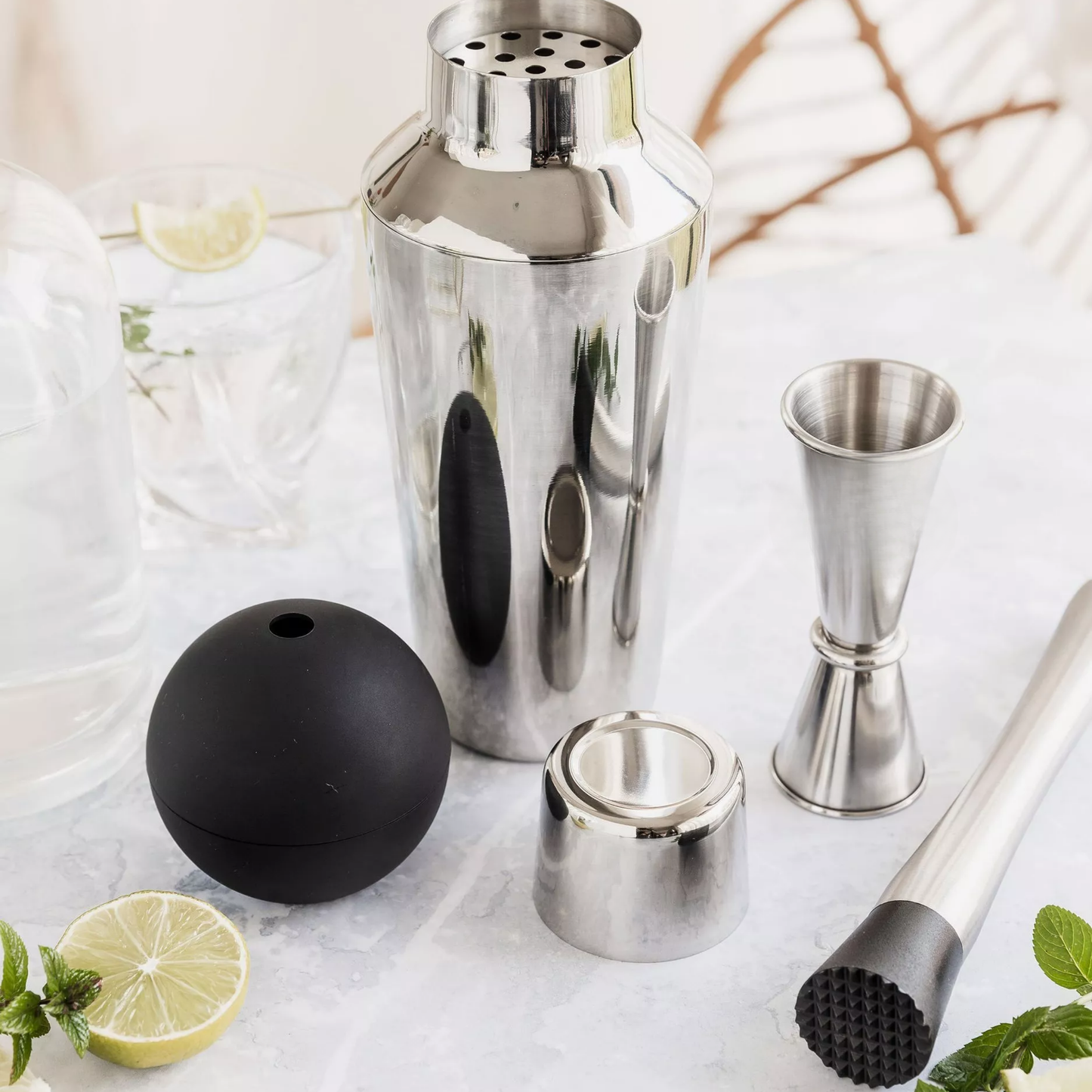 Spirit jigger on display with cocktail equipment with citrus and mint